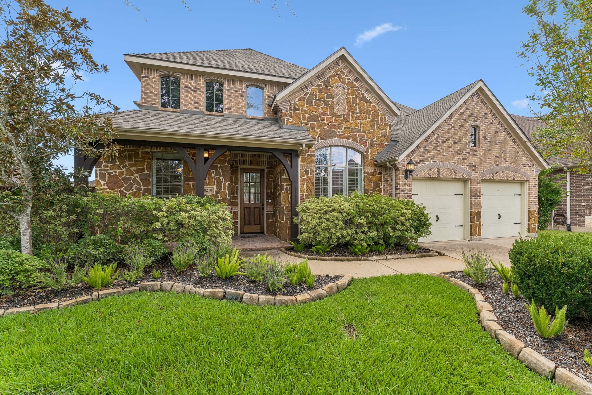 8210 Thunder Ridge Way, Missouri City, TX 77459 Charming brick and stone faade with a welcoming front porch and lush landscaping.