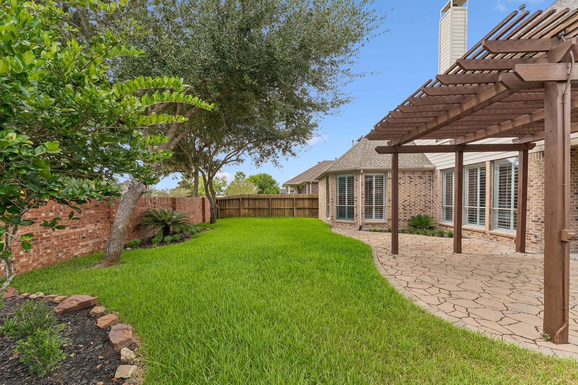8210 Thunder Ridge Way, Missouri City, TX 77459 Tranquil backyard oasis with lush greenery and a charming pergola, perfect for relaxation and outdoor gatherings.