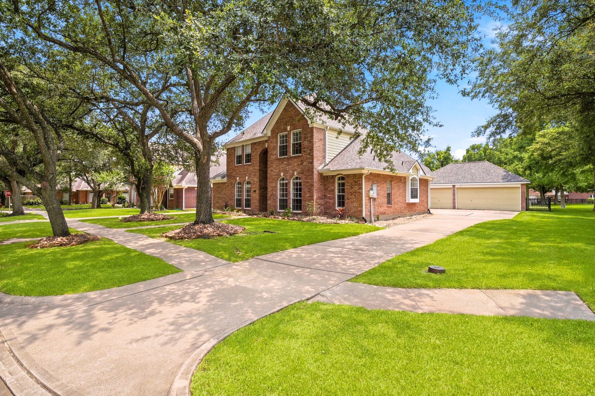 2216 Fairwater Park Drive, League City, TX 77573 Charming two-story brick home nestled in a peaceful, suburban setting, featuring a large front yard with mature trees, a well-maintained lawn, and a paved driveway leading to a spacious attached garage.