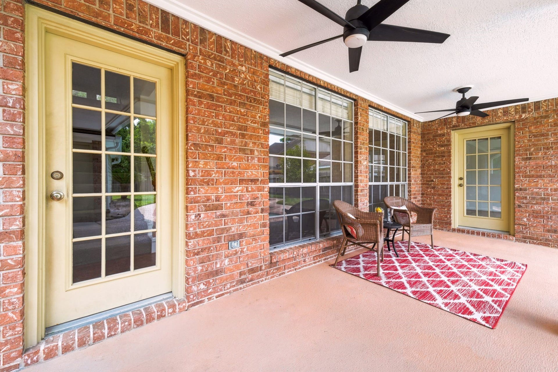 2216 Fairwater Park Drive, League City, TX 77573 Experience relaxation on the charming covered patio, featuring elegant brick walls, two ceiling fans, and large windows for a perfect blend of comfort and style.