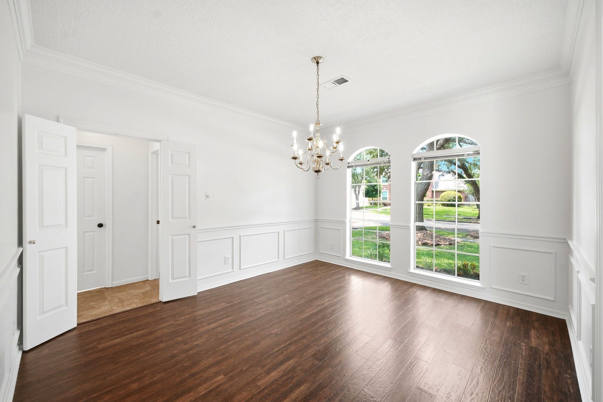 2216 Fairwater Park Drive, League City, TX 77573 Bright and inviting, this elegant dining room boasts large windows, rich hardwood floors, and a classic chandelier, providing the perfect blank canvas for your personal touch.