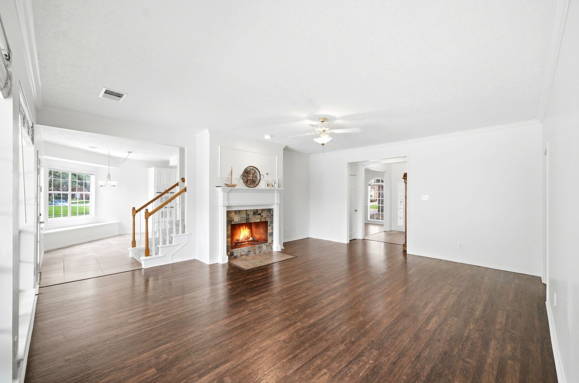 2216 Fairwater Park Drive, League City, TX 77573 Expansive living room with elegant floors and a cozy fireplace, seamlessly connected to a tiled breakfast room and stairs leading to the inviting upstairs bedrooms.