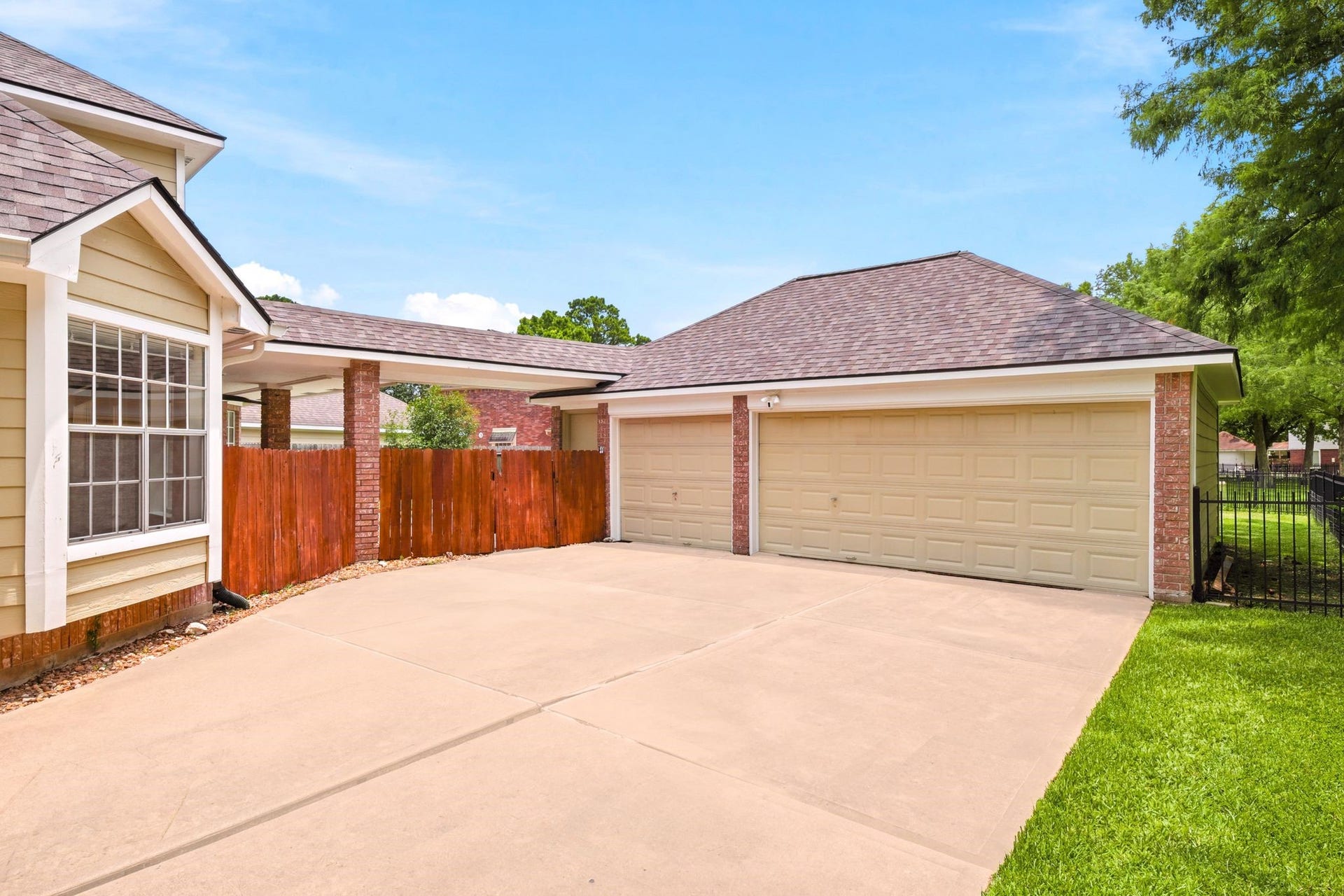 2216 Fairwater Park Drive, League City, TX 77573 A spacious driveway leads to a two-car garage, bordered by a charming wooden fence that guides you to the inviting pool and expansive backyard.