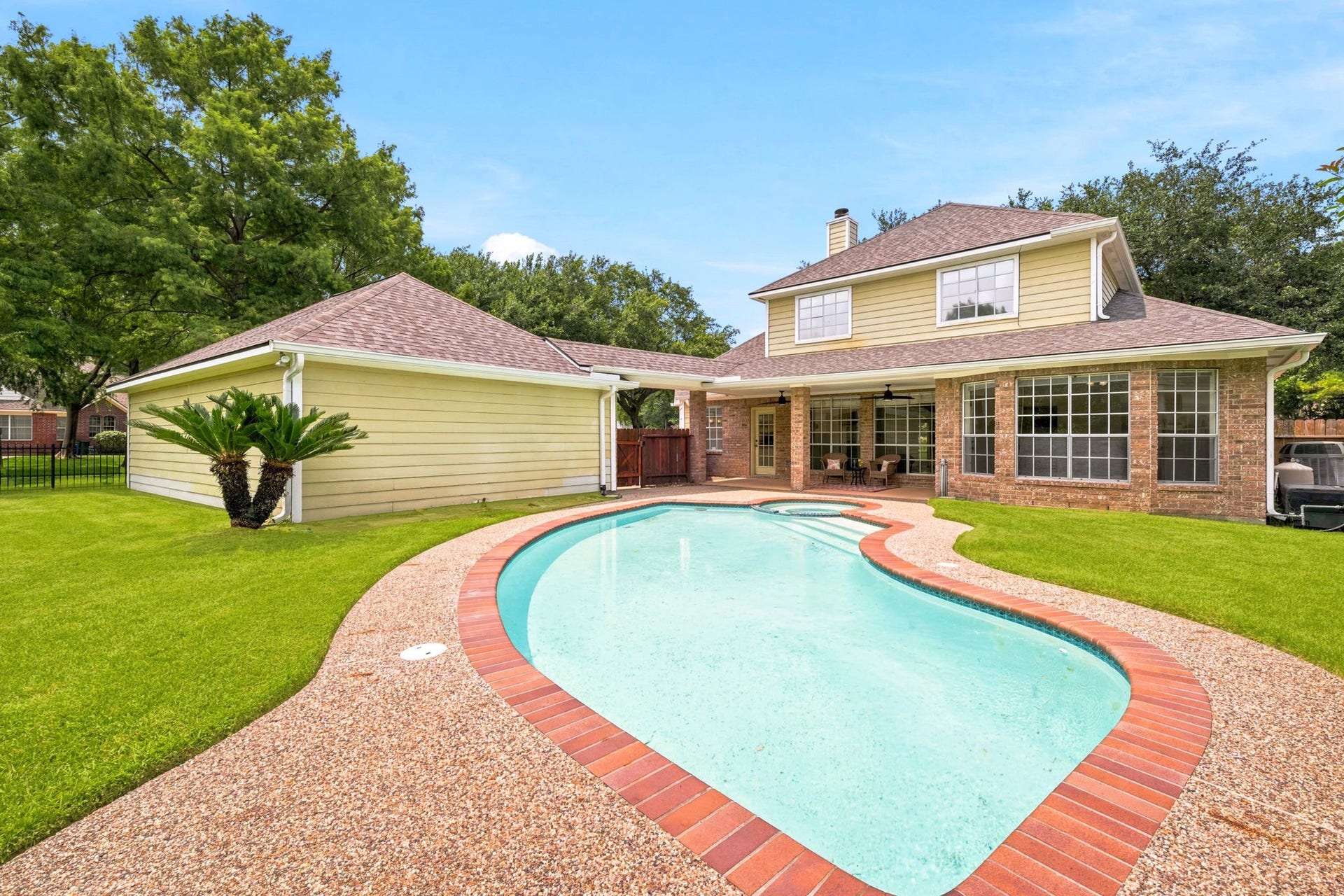 2216 Fairwater Park Drive, League City, TX 77573 Charming two-story home with a spacious backyard oasis, featuring a sparkling pool nestled among lush grass and mature trees, and a covered patio perfect for outdoor relaxation and entertaining.