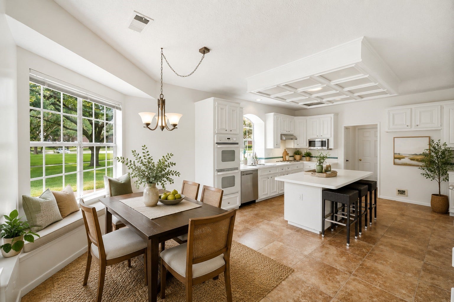 2216 Fairwater Park Drive, League City, TX 77573 Experience the perfect blend of style and comfort in this bright kitchen, featuring elegant white cabinetry, a central island with bar seating, and a cozy dining nook with large windows offering serene views of a lush green yard.