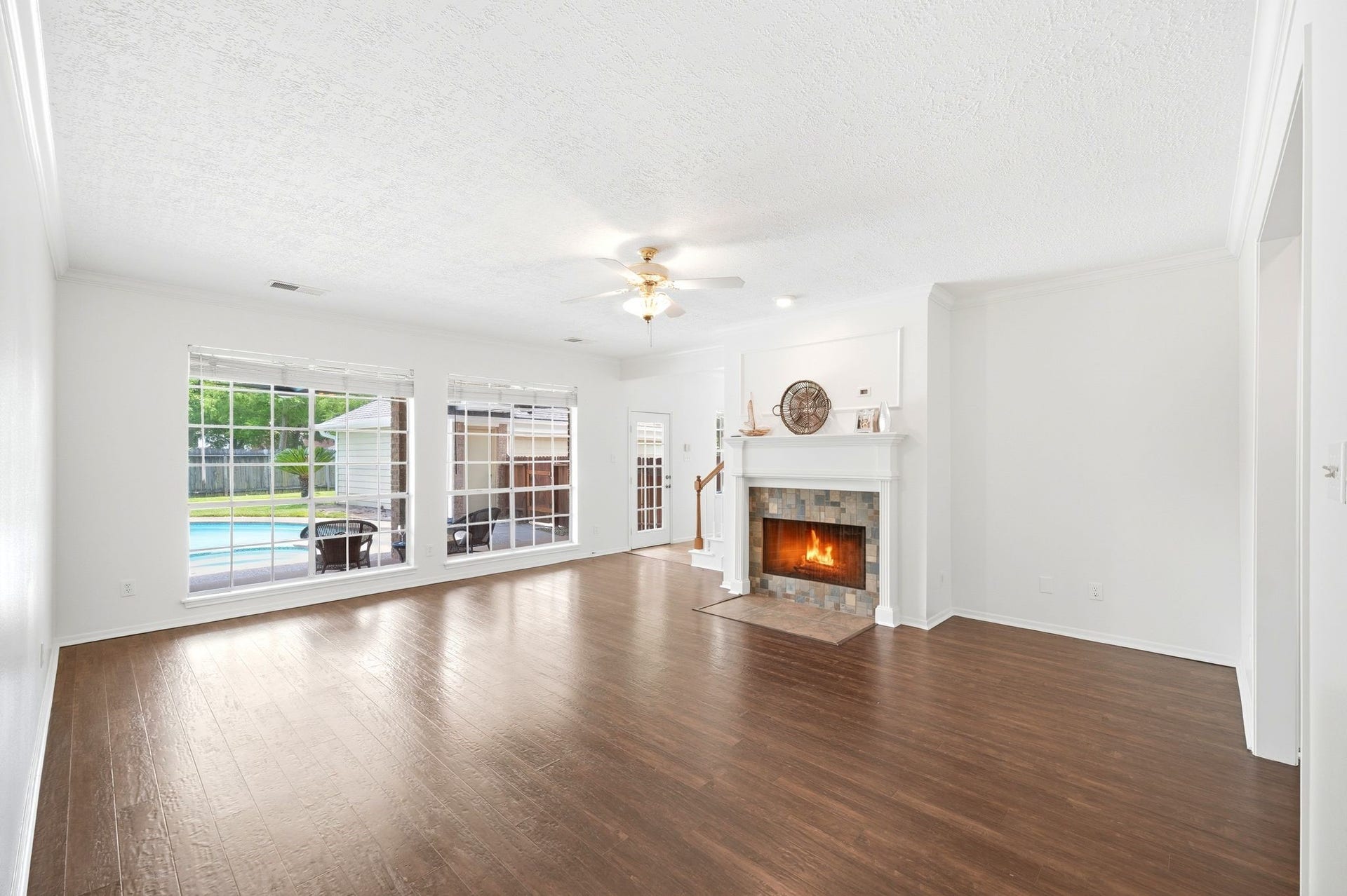 2216 Fairwater Park Drive, League City, TX 77573 Spacious and bright, this living room features elegant floors, a cozy fireplace, and large windows offering serene views of the pool, perfect for creating your dream space.