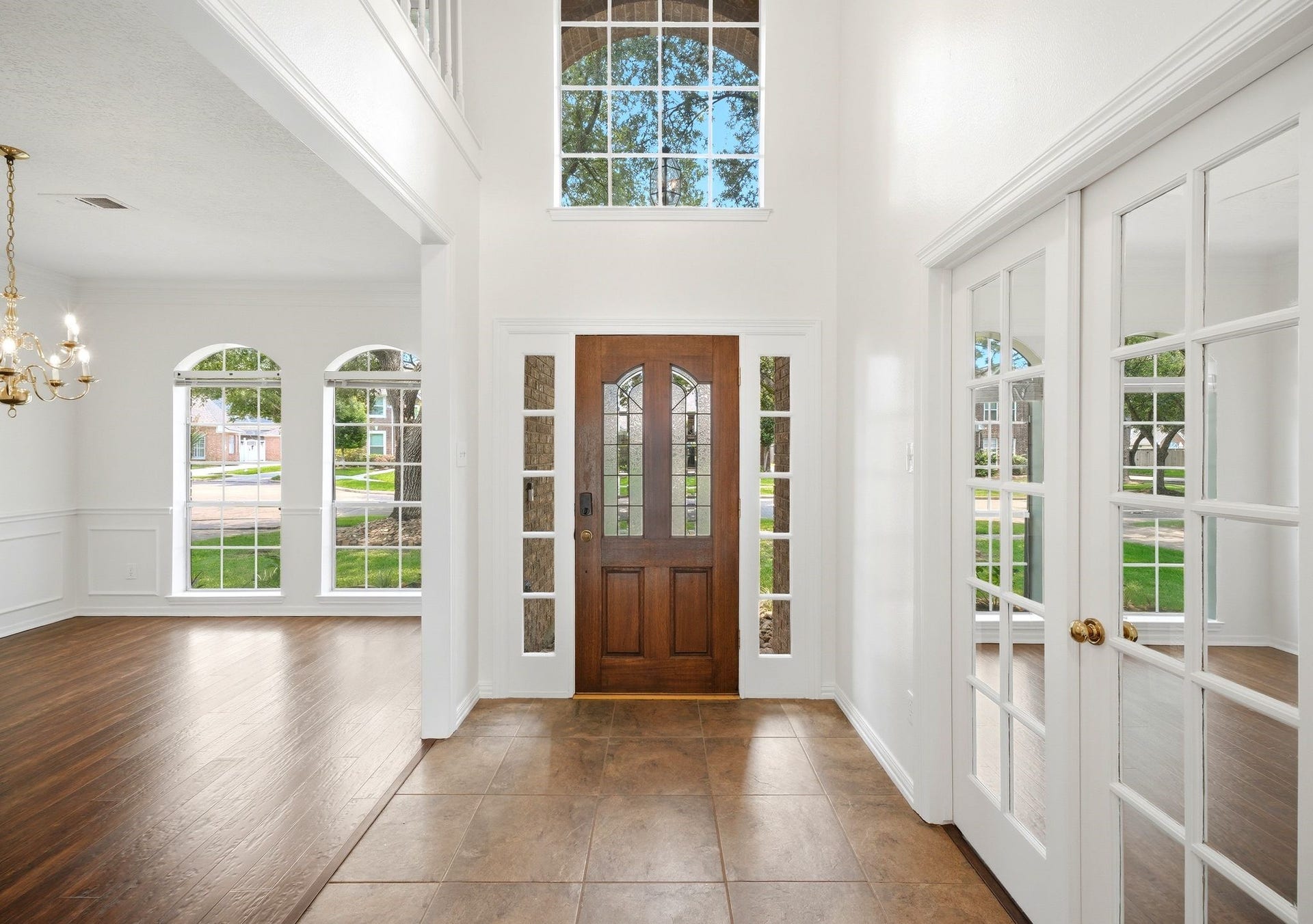 2216 Fairwater Park Drive, League City, TX 77573 Step into a stunning entryway with soaring ceilings and abundant natural light, featuring a stylish wooden front door with glass panels and elegant French doors leading to the formal dining room and home office.