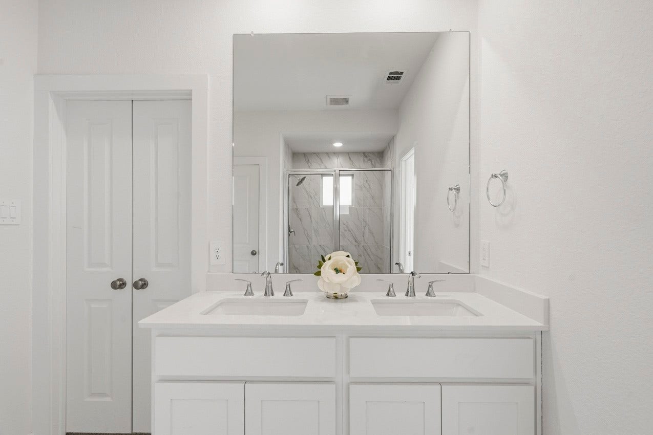 3431 Loam Lane, Richmond, TX 77406 The primary bathroom features crisp white cabinetry and a large mirror, creating a bright, timeless, and sophisticated retreat.