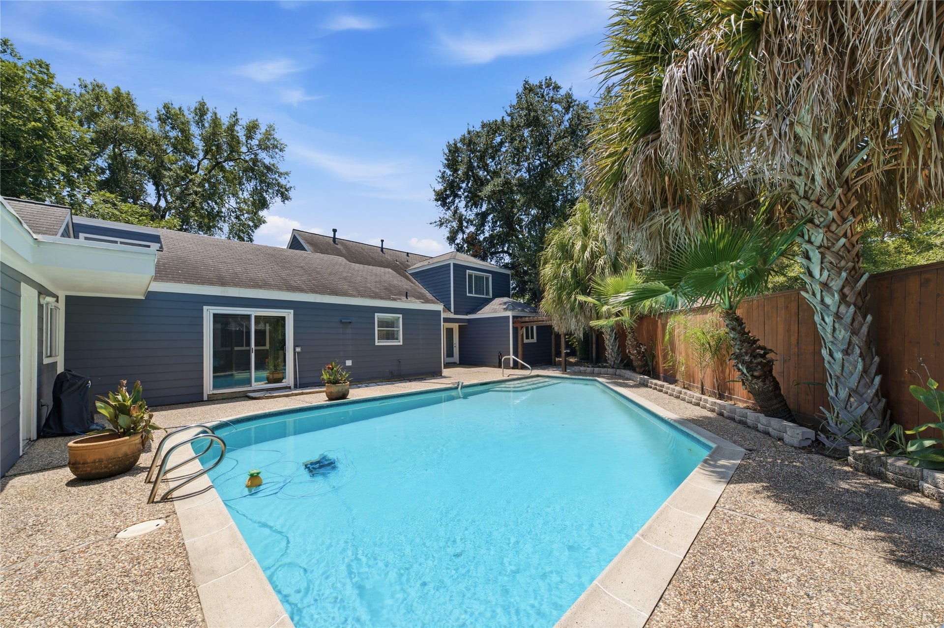 703 Queensmill Court, Houston, TX 77079 Tropical paradise in your own backyard, complete with lush palms and a sun-drenched pool deck.