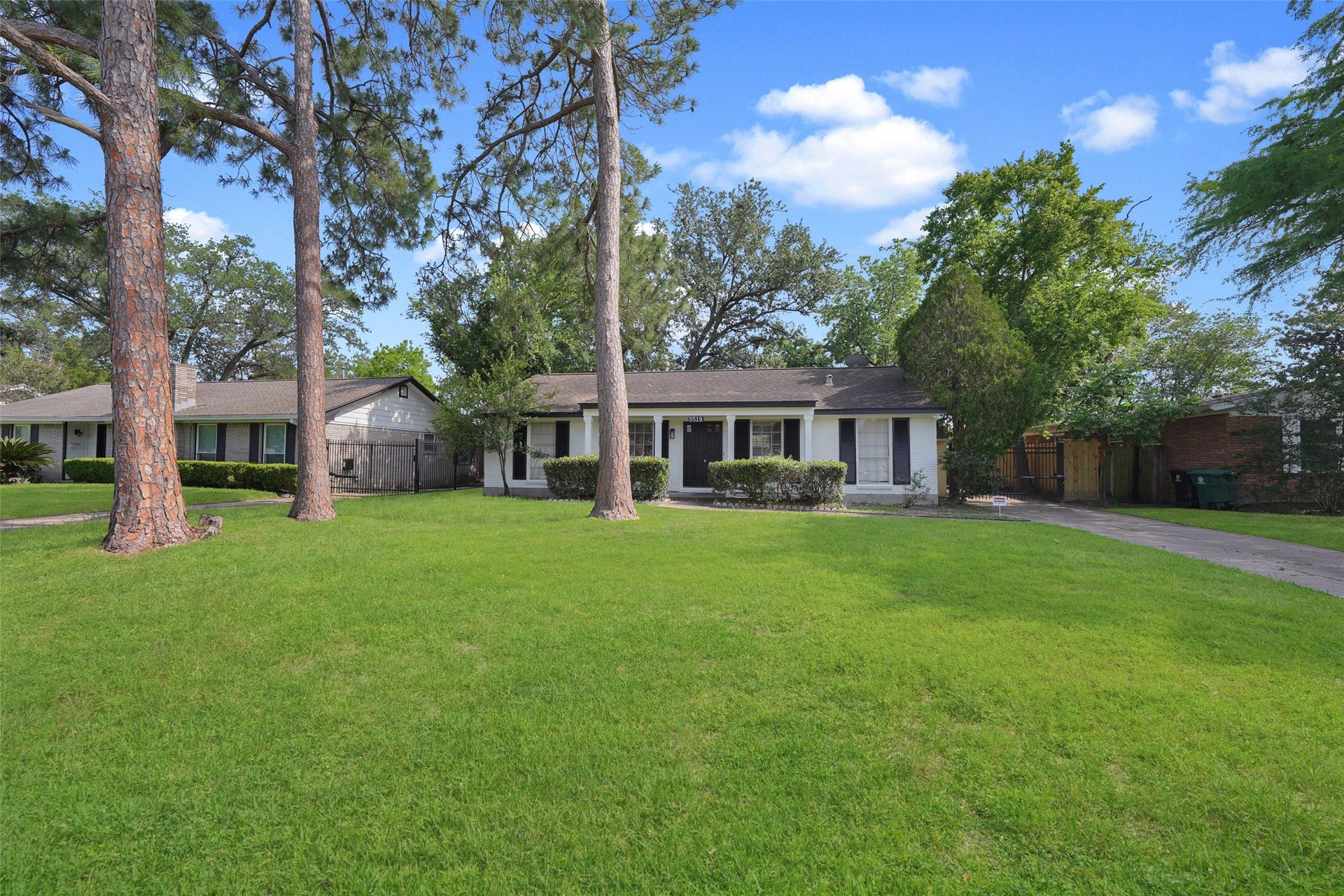 9519 Val Verde Street, Houston, TX 77063 Charming single-story home with a spacious front yard featuring mature trees. The house has a classic design with a welcoming porch and a long driveway, offering ample space for parking and outdoor activities.