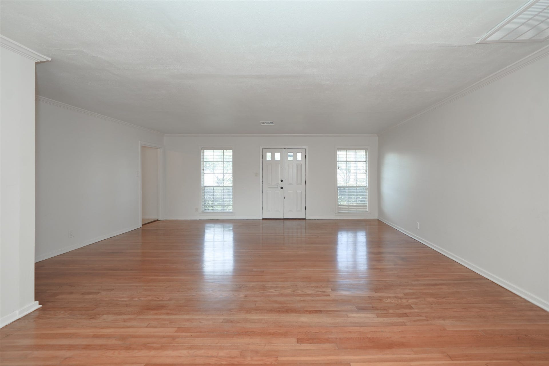 9519 Val Verde Street, Houston, TX 77063 This spacious living room features polished hardwood floors, two large windows for natural light, and a central front door, creating a bright and welcoming entryway.