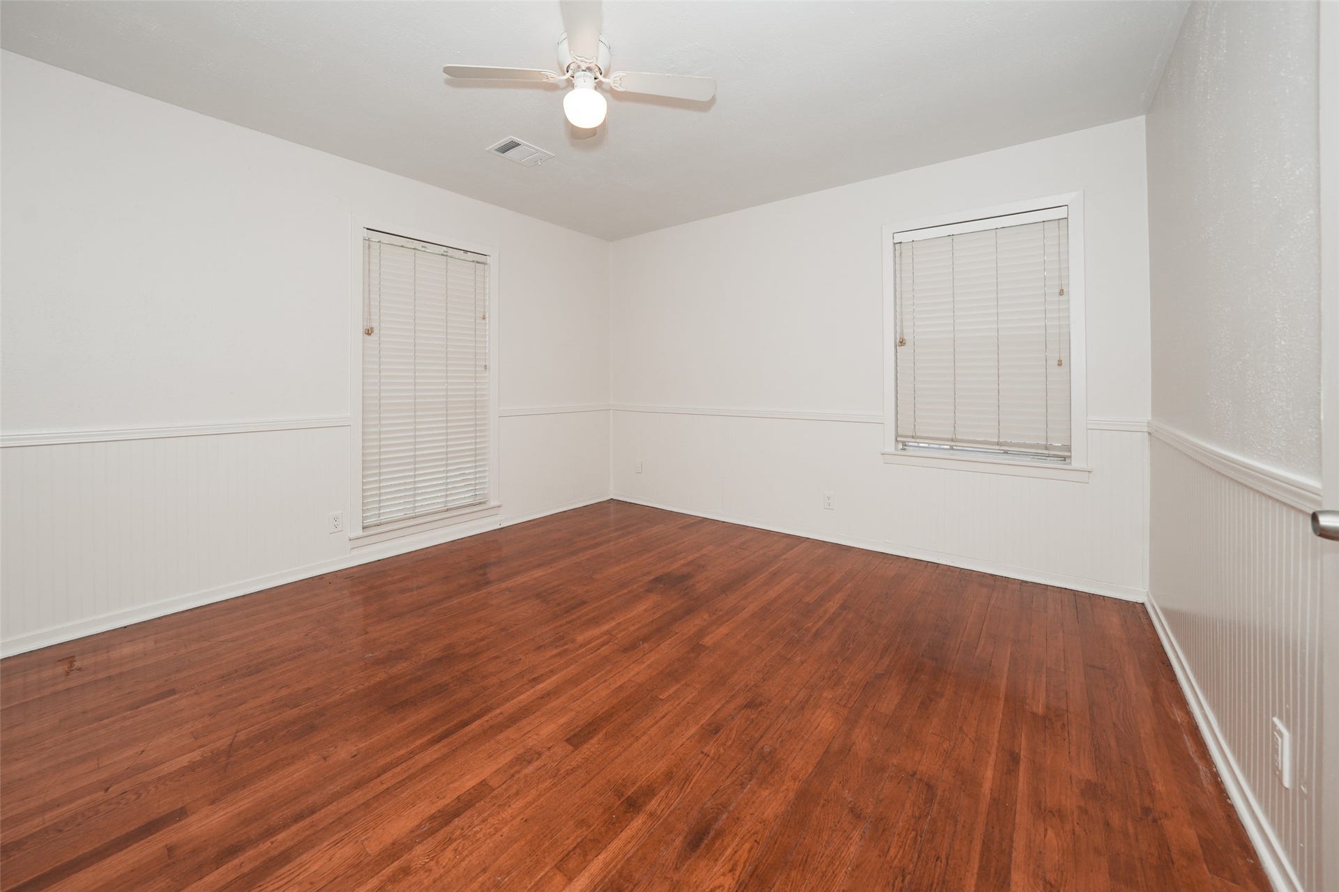 9519 Val Verde Street, Houston, TX 77063 This room features polished hardwood floors, neutral walls, and a ceiling fan, creating a bright and airy space perfect for a bedroom or office. The windows have blinds for privacy and light control.