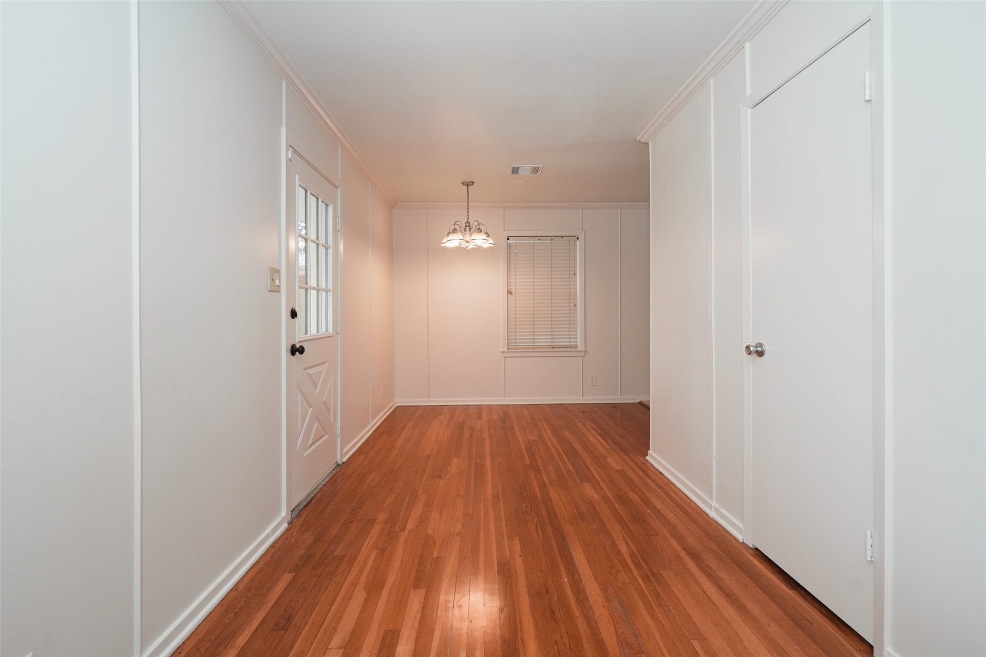 9519 Val Verde Street, Houston, TX 77063 This room features warm hardwood flooring, white walls, and a central light fixture. It includes a window with blinds, a door, and a closet, offering a cozy, versatile space.