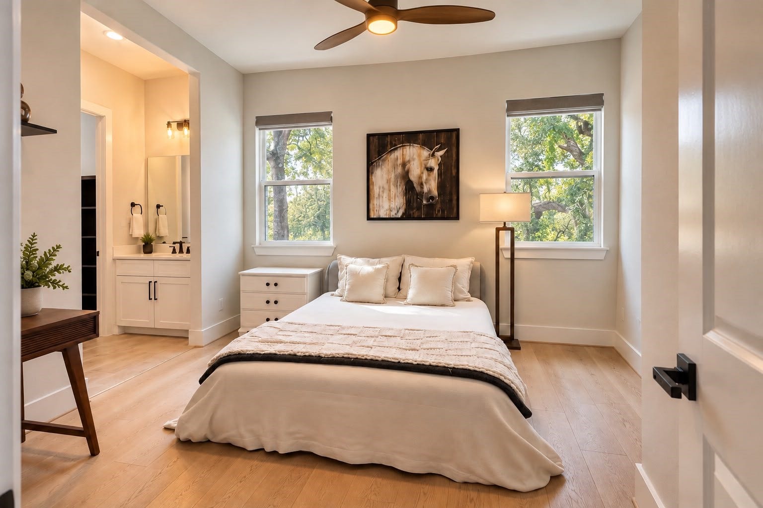 413 Forest Reserve Place, Houston, TX 77079 Bright and inviting bedroom featuring large windows with serene tree views, light wood flooring, a modern ceiling fan, and an ensuite vanity area.