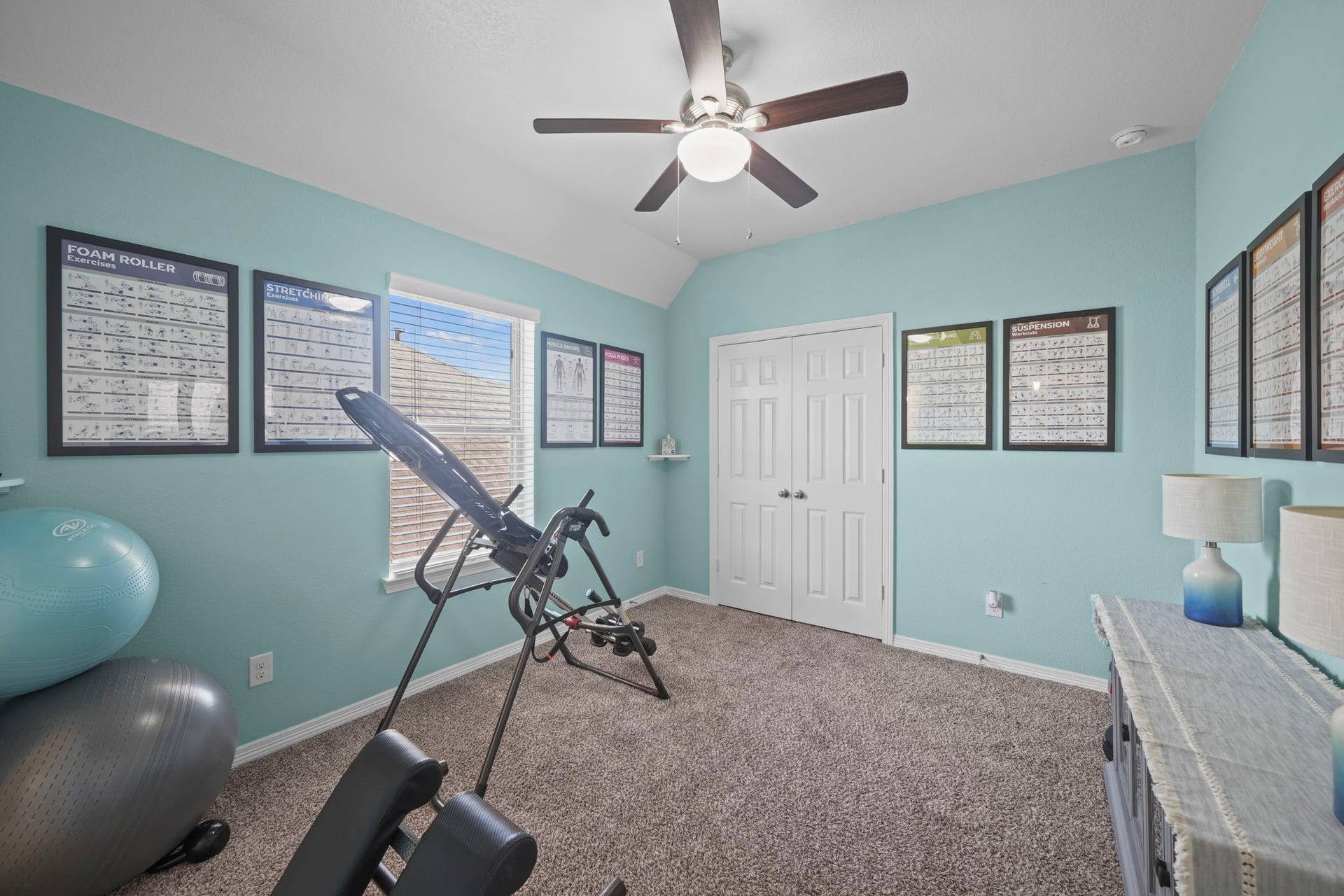 28107 Scenic Shore Lane, Fulshear, TX 77441 Bright and inviting exercise room featuring a ceiling fan, ample natural light, and motivational wall posters, perfect for home workouts.