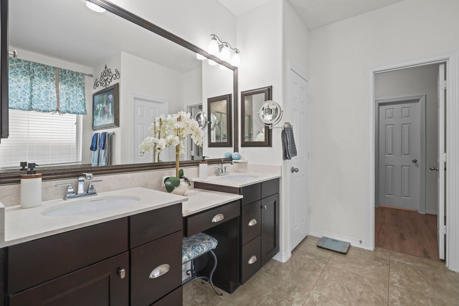 28107 Scenic Shore Lane, Fulshear, TX 77441 Elegant bathroom featuring a double vanity with dark cabinetry and ample countertop space, complemented by a large mirror and stylish lighting.