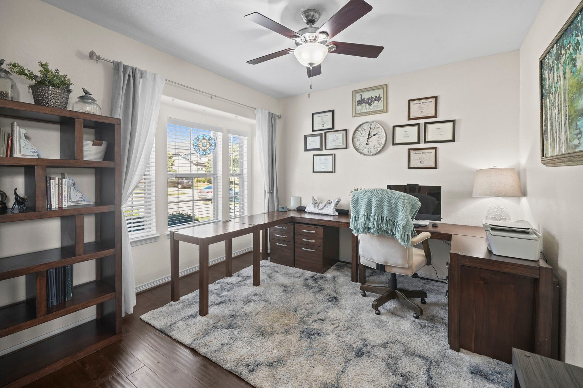28107 Scenic Shore Lane, Fulshear, TX 77441 Bright and inviting home office featuring large windows, elegant wood flooring, and a stylish desk setup complemented by ample shelving and tasteful decor.