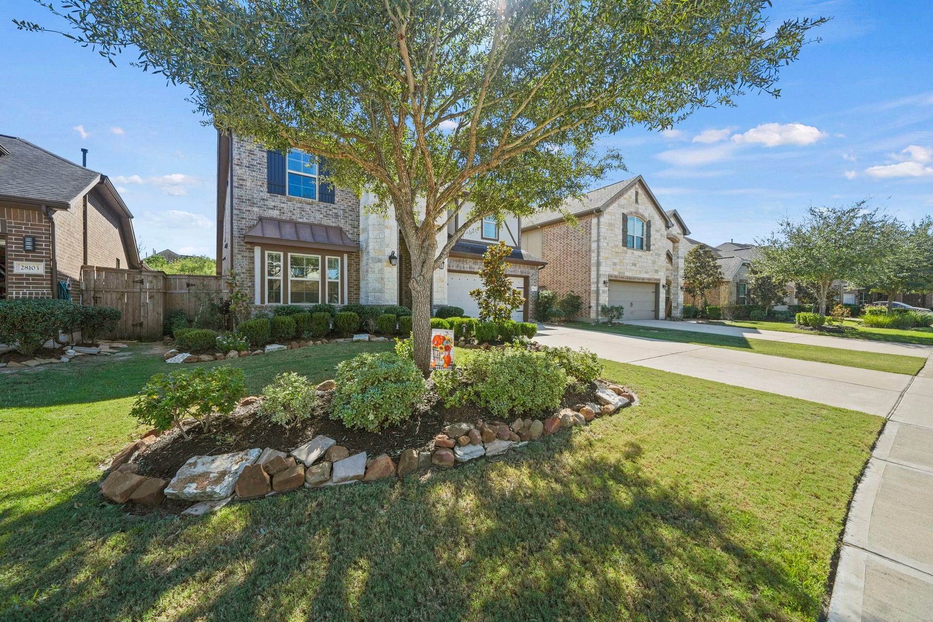 28107 Scenic Shore Lane, Fulshear, TX 77441 Charming two-story home with a beautifully landscaped front yard featuring a mature tree and well-maintained shrubs, set in a peaceful neighborhood.