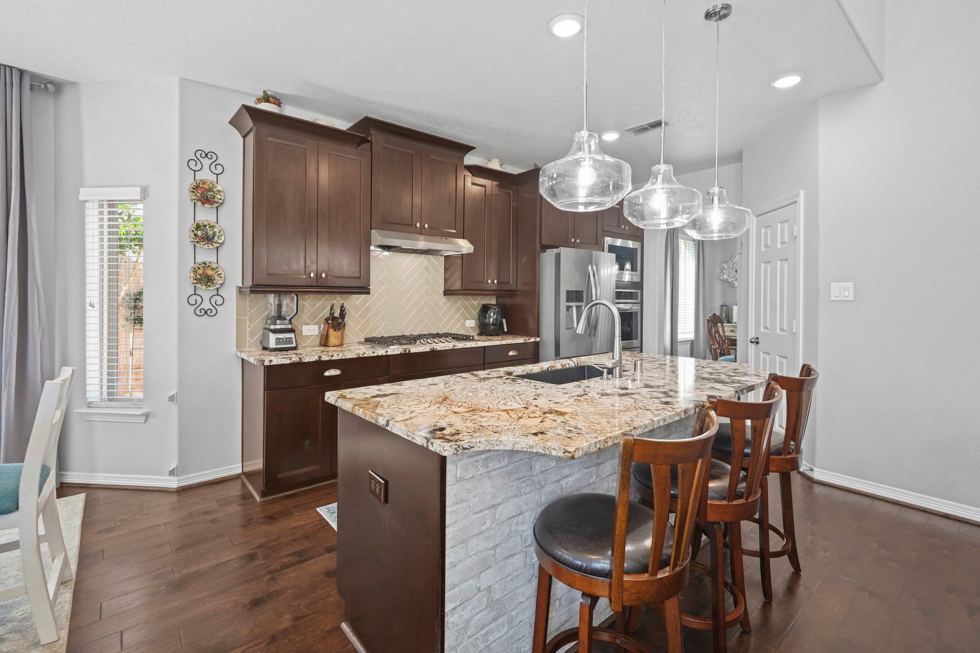 28107 Scenic Shore Lane, Fulshear, TX 77441 Elegant kitchen featuring rich wood cabinets, a stunning granite island with seating, and modern stainless steel appliances.