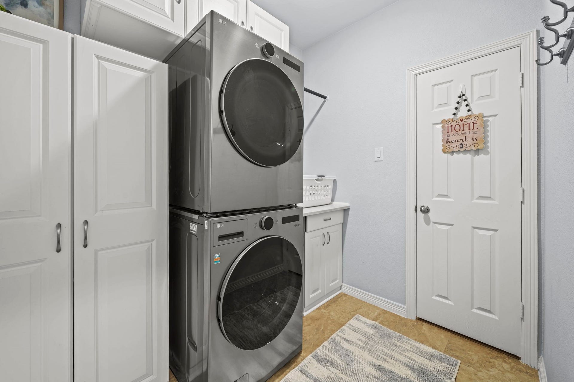 28107 Scenic Shore Lane, Fulshear, TX 77441 Efficient laundry room featuring modern stacked washer and dryer, ample cabinetry for storage, and a convenient folding counter.