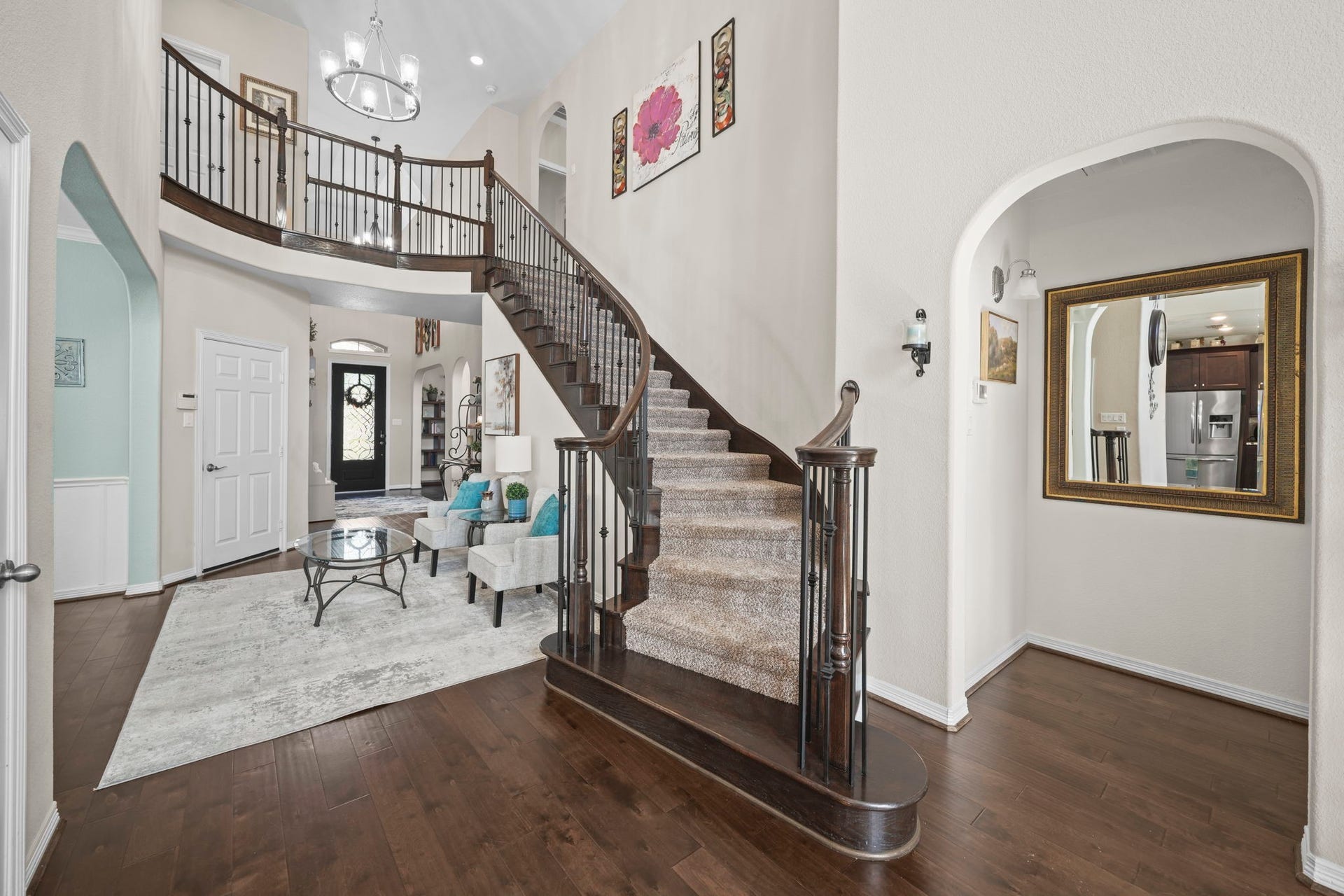 28107 Scenic Shore Lane, Fulshear, TX 77441 Elegant foyer with a grand curved staircase, rich hardwood floors, and an inviting living area perfect for entertaining.
