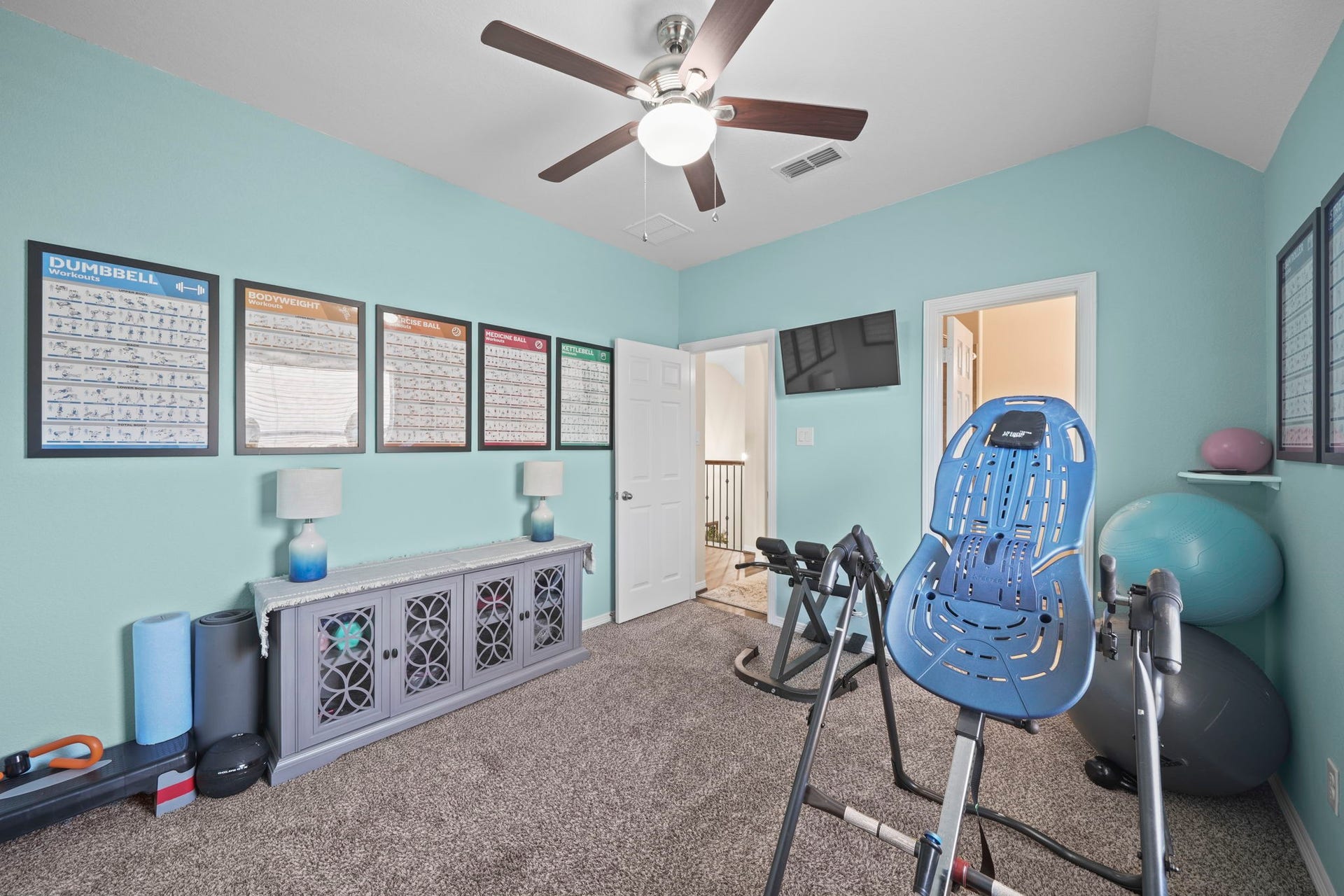 28107 Scenic Shore Lane, Fulshear, TX 77441 Bright and airy home gym with modern equipment, exercise guides, and a ceiling fan, perfect for fitness enthusiasts.