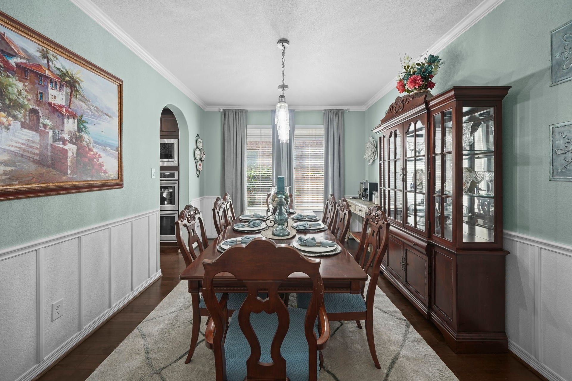 28107 Scenic Shore Lane, Fulshear, TX 77441 Elegant dining room featuring a classic wooden table set, a sophisticated china cabinet, and tasteful wall art, all illuminated by natural light from large windows.