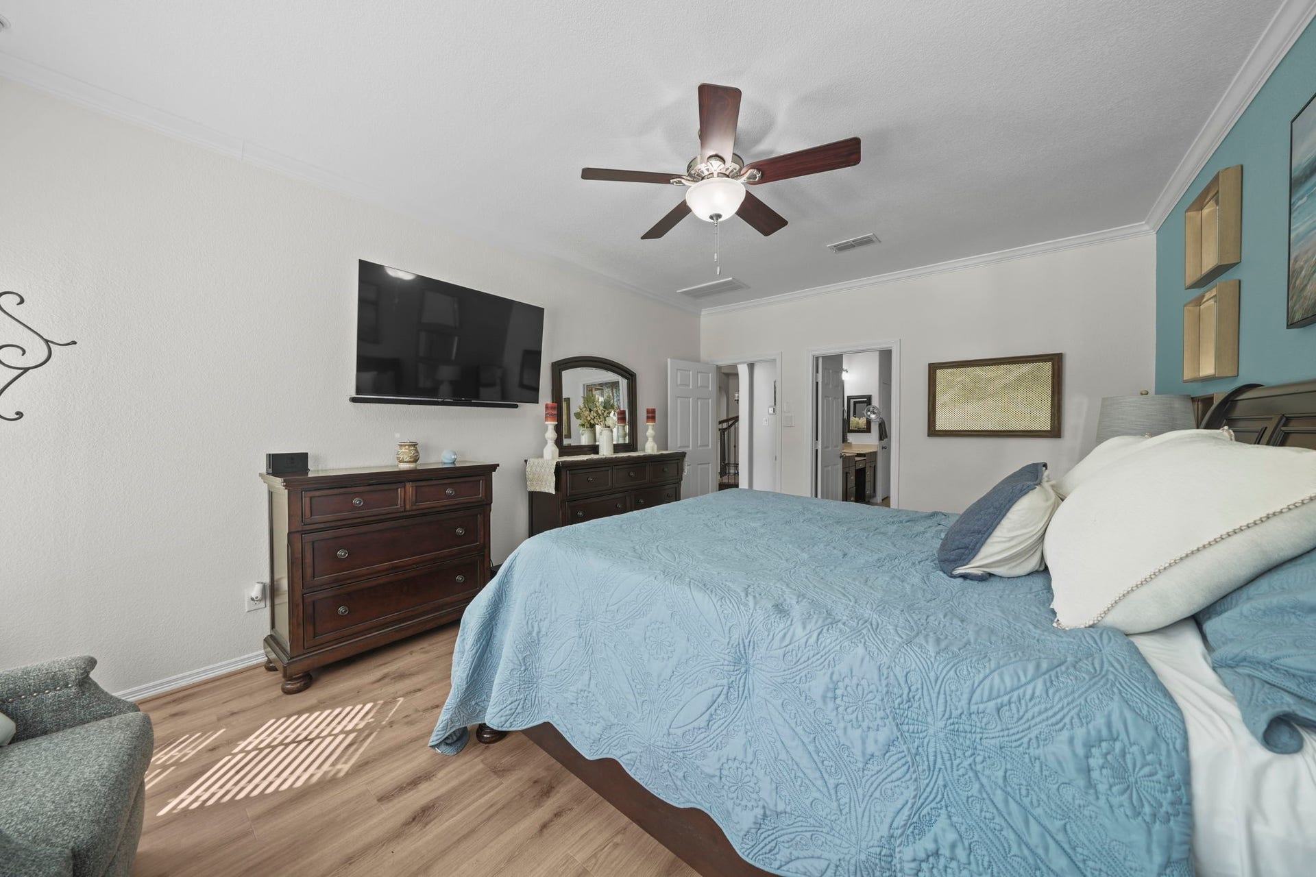 28107 Scenic Shore Lane, Fulshear, TX 77441 Spacious bedroom featuring a cozy blue bedding set, elegant wooden furniture, and a ceiling fan, creating a relaxing retreat.