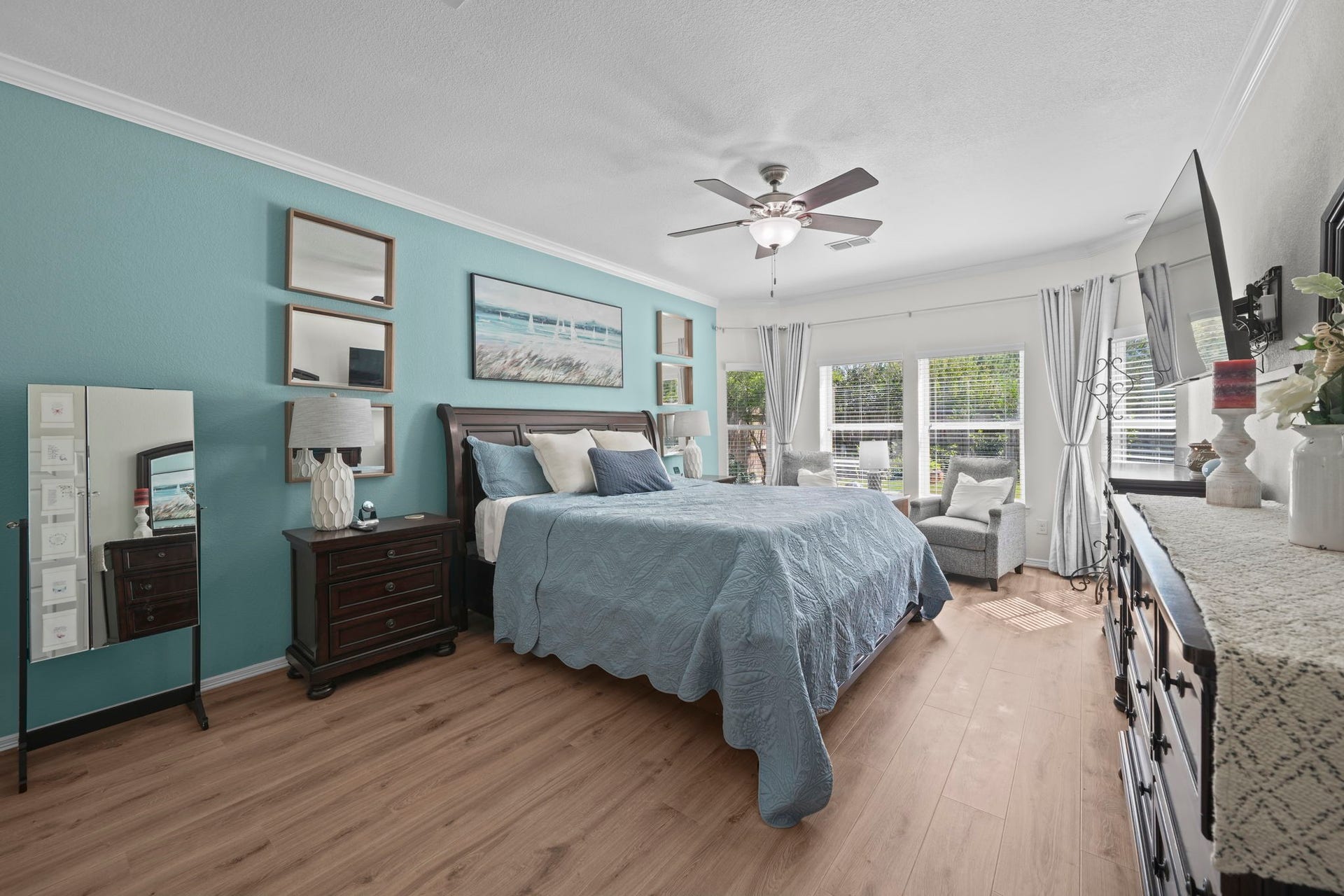 28107 Scenic Shore Lane, Fulshear, TX 77441 Spacious and bright bedroom featuring a cozy sitting area by large windows, elegant wood flooring, and stylish decor with a calming color palette.