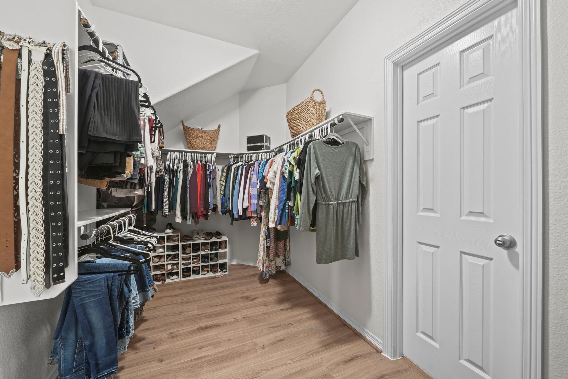 28107 Scenic Shore Lane, Fulshear, TX 77441 Spacious walk-in closet with ample hanging space, shelving, and shoe storage, featuring a sleek, organized layout with hardwood floors.