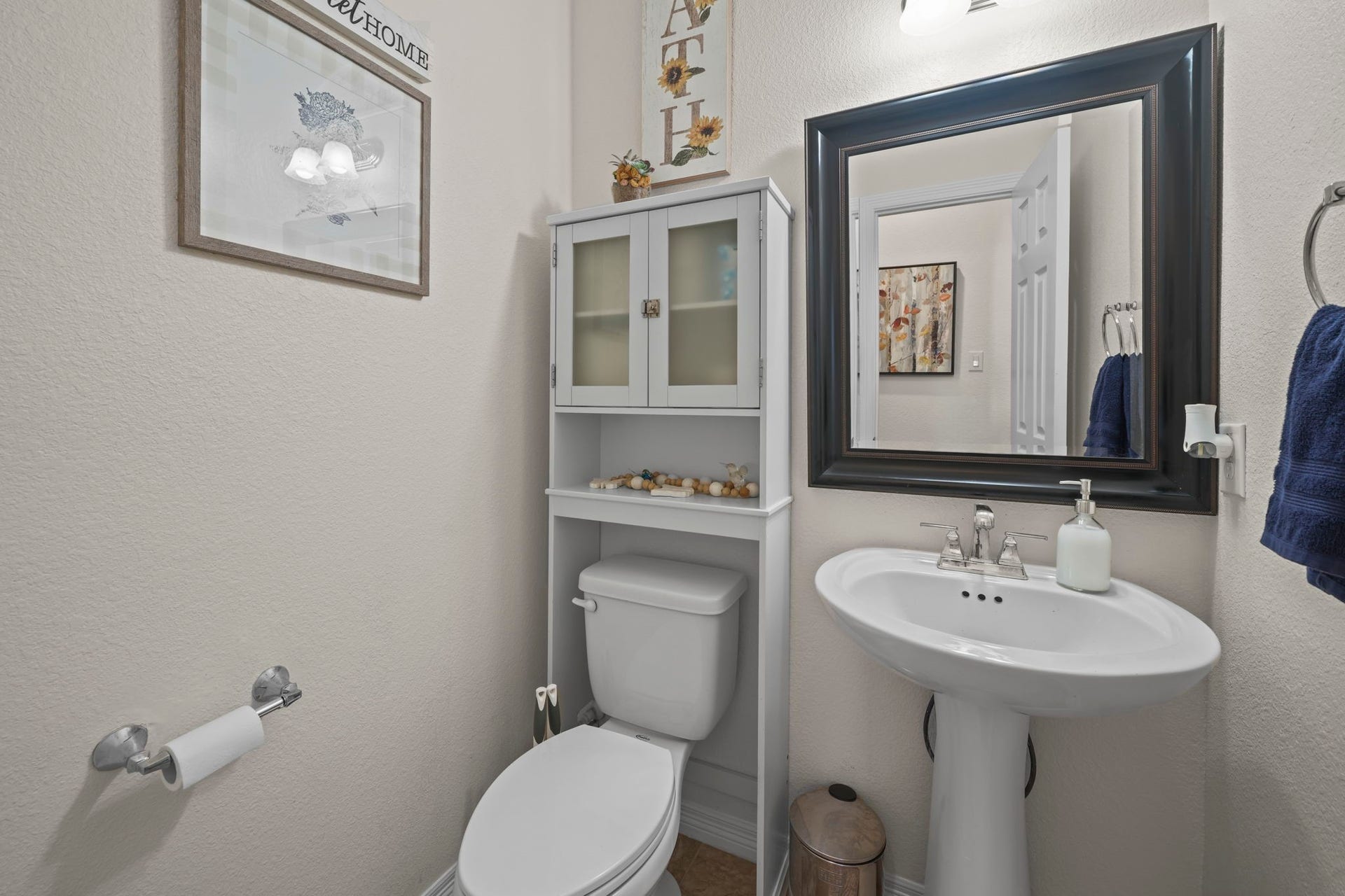 28107 Scenic Shore Lane, Fulshear, TX 77441 Charming and efficient powder room featuring a sleek pedestal sink, elegant wall mirror, and convenient storage above the toilet.