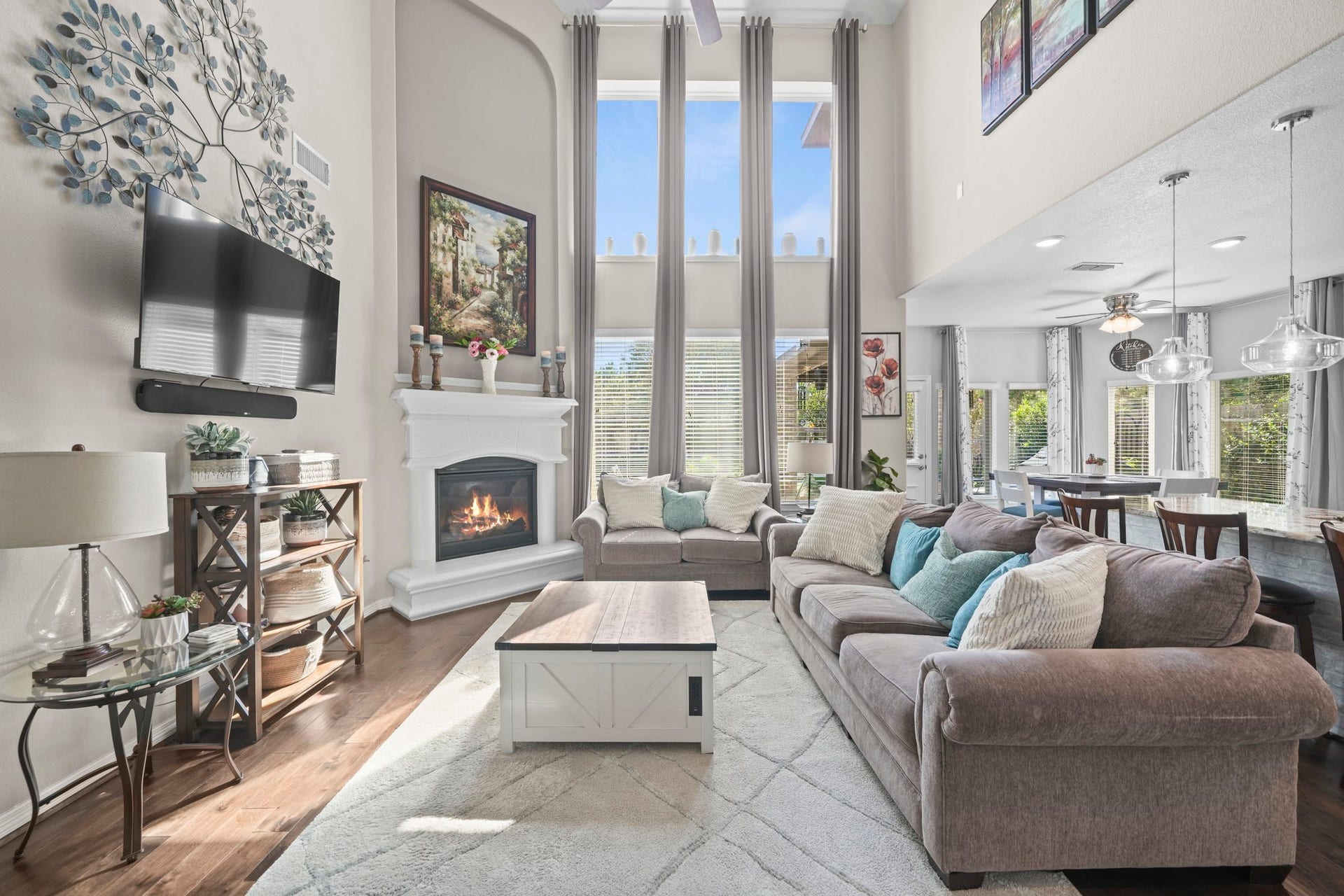 28107 Scenic Shore Lane, Fulshear, TX 77441 Spacious and elegant living area with soaring ceilings and abundant natural light, featuring a cozy fireplace, modern decor, and an open layout connecting to the dining area and kitchen.