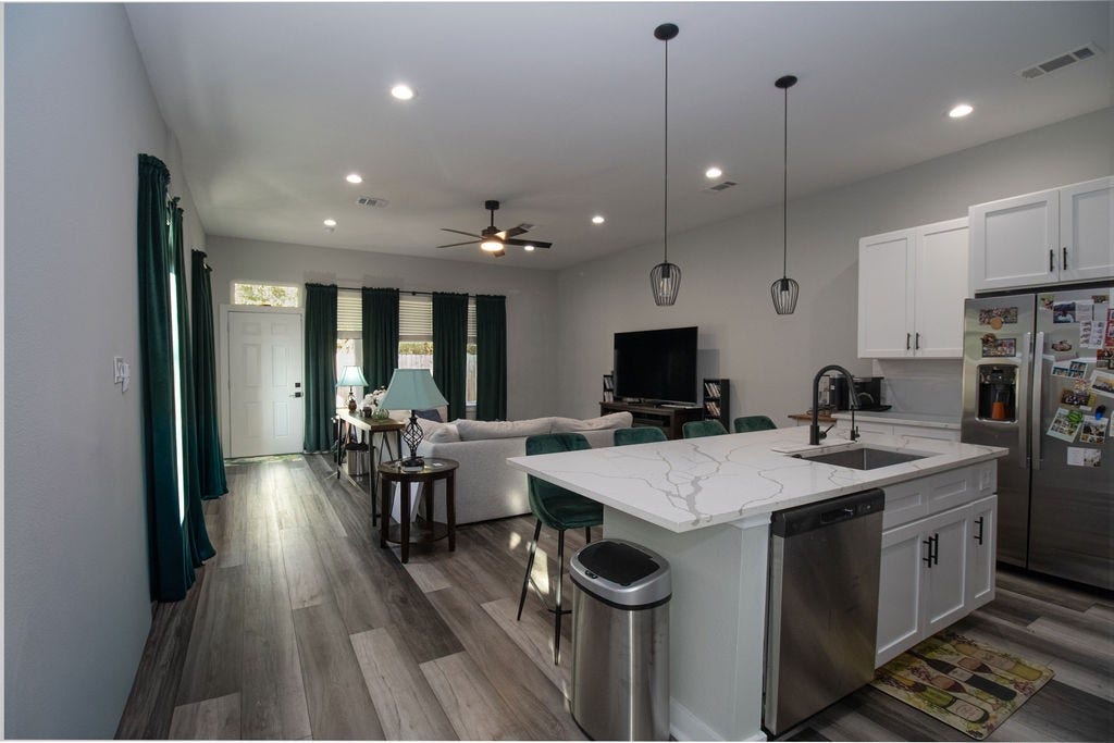 8415 Sunnyhill Street, #B, Houston, TX 77088 Beautifully designed kitchen featuring white shaker-style cabinetry, stainless steel appliances, attractive countertops, stylish pendant lighting, and an oversized island with seating for four. A wonderful space for gathering and entertaining!