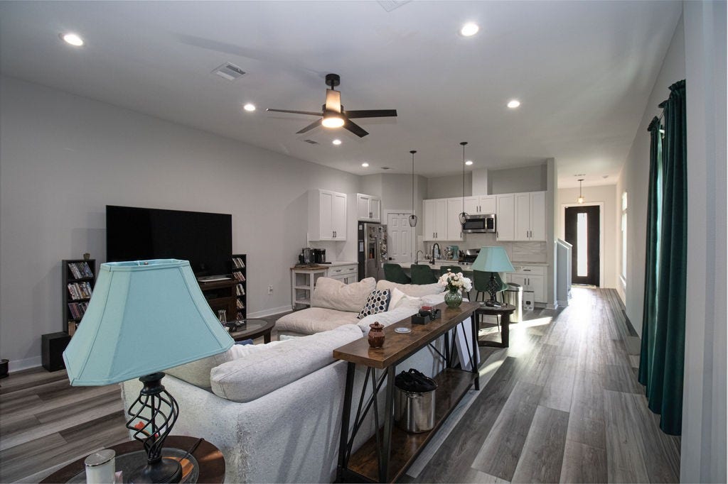 8415 Sunnyhill Street, #B, Houston, TX 77088 Bright and welcoming living area featuring multiple windows, attractive wood-look flooring, a modern ceiling fan, and plenty of room for comfortable seating and entertaining.