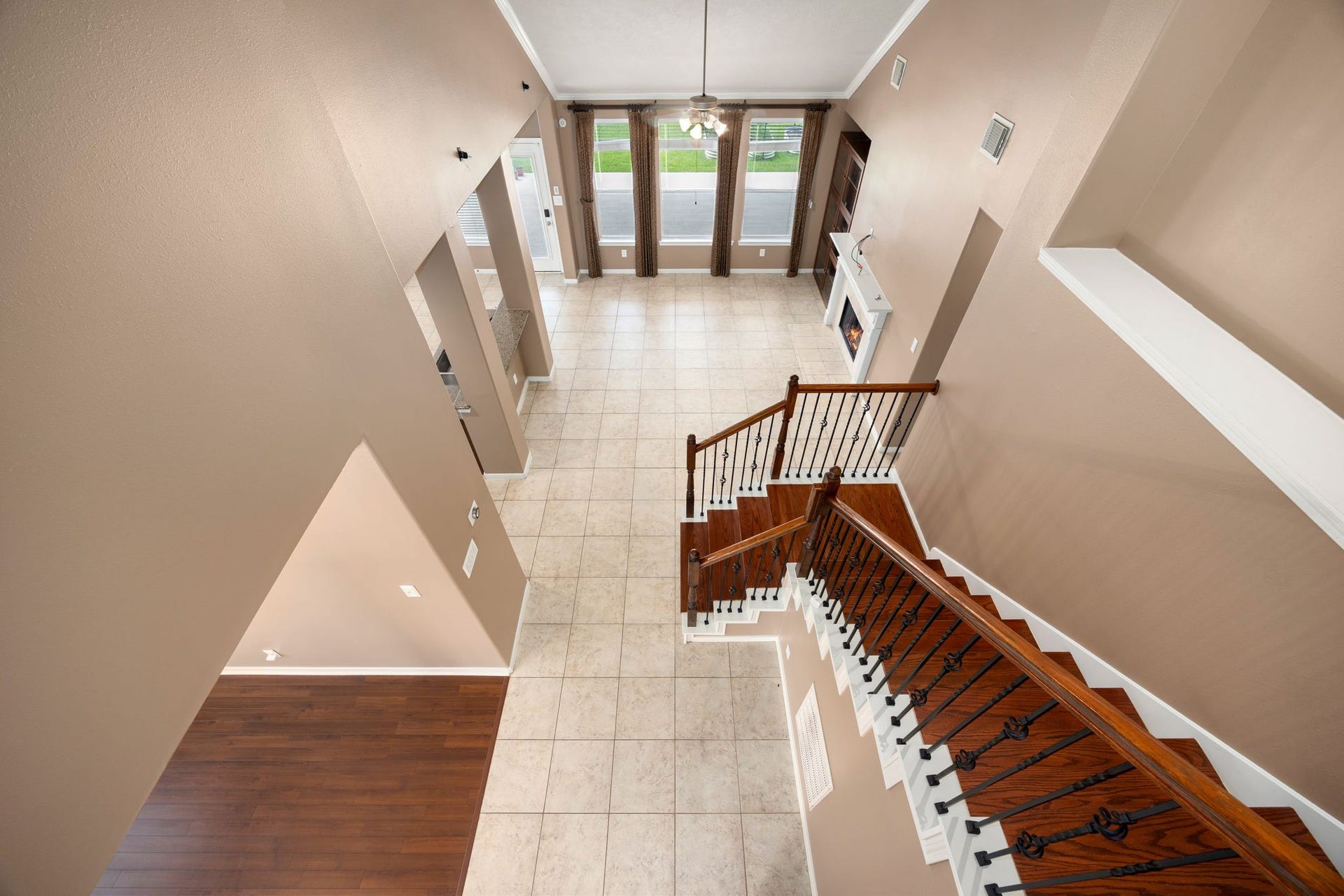 This impressive upstairs view provides an excellent look at the homes functional floor plan. Watch how the rich wood-tread staircase overlooks the expansive tile flooring below, seamlessly connecting the main living areas, the kitchen breakfast bar, and the formal dining space.