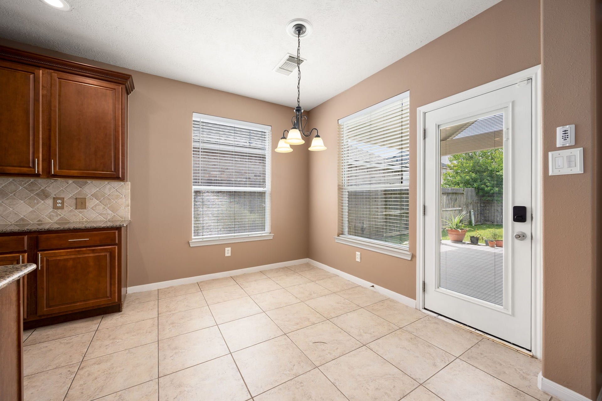 Enjoy casual meals in this sunlit breakfast nook located right off the kitchen. Surrounded by large windows and a glass door, it offers peaceful views and seamless access to the backyard patio, perfect for morning coffee.