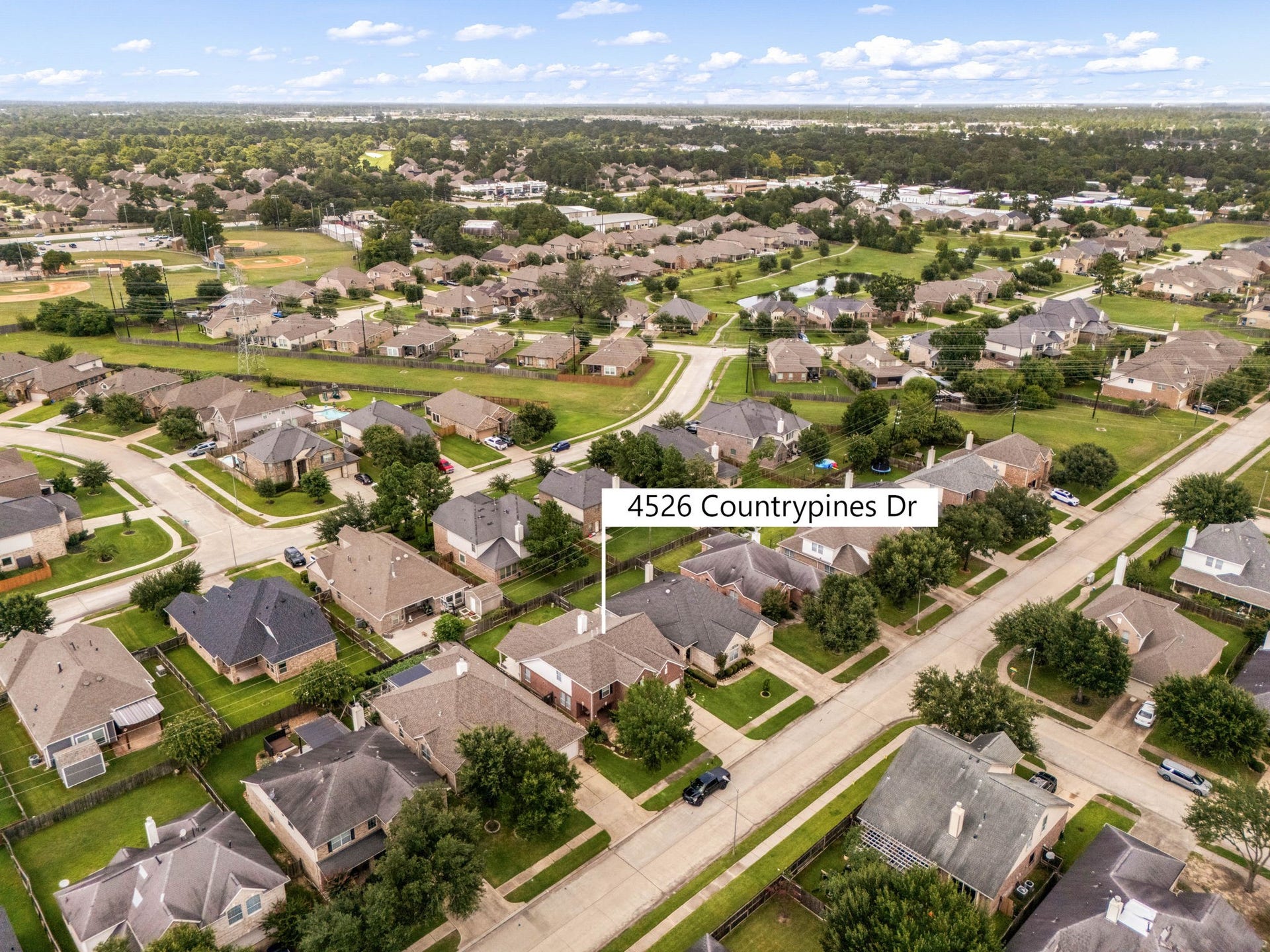 Welcome to Country Lakes Estates! This drone view showcases the expansive layout of the neighborhood, highlighting the mature trees, uniform streets, and clean curb appeal surrounding the property. A perfect snapshot of a thriving, welcoming Texas community.