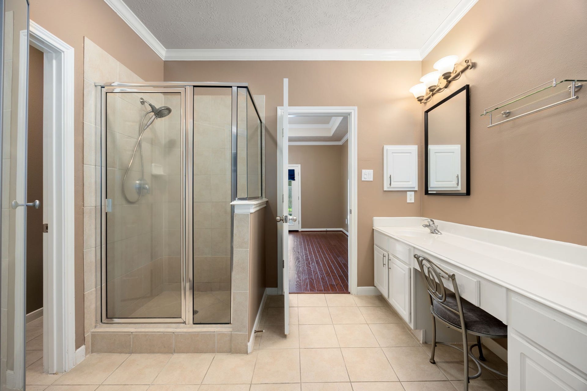 This additional view of the primary bathroom highlights a separate, glass-enclosed walk-in shower with tile surround.