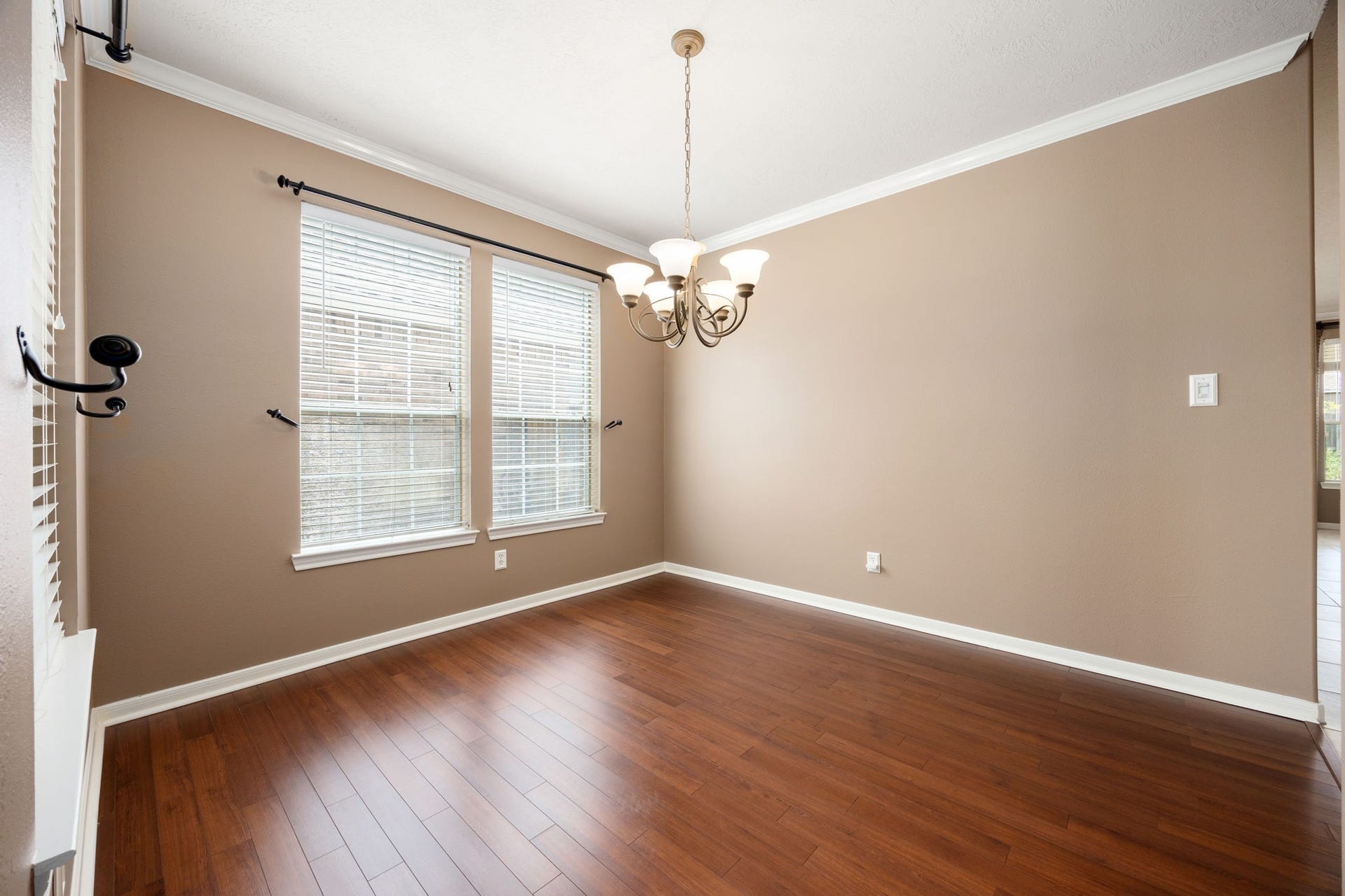 Host memorable dinners in this elegant formal dining room. The space is beautifully appointed with rich wood-look flooring, classic crown molding, a decorative chandelier, and large windows that flood the room with natural light.