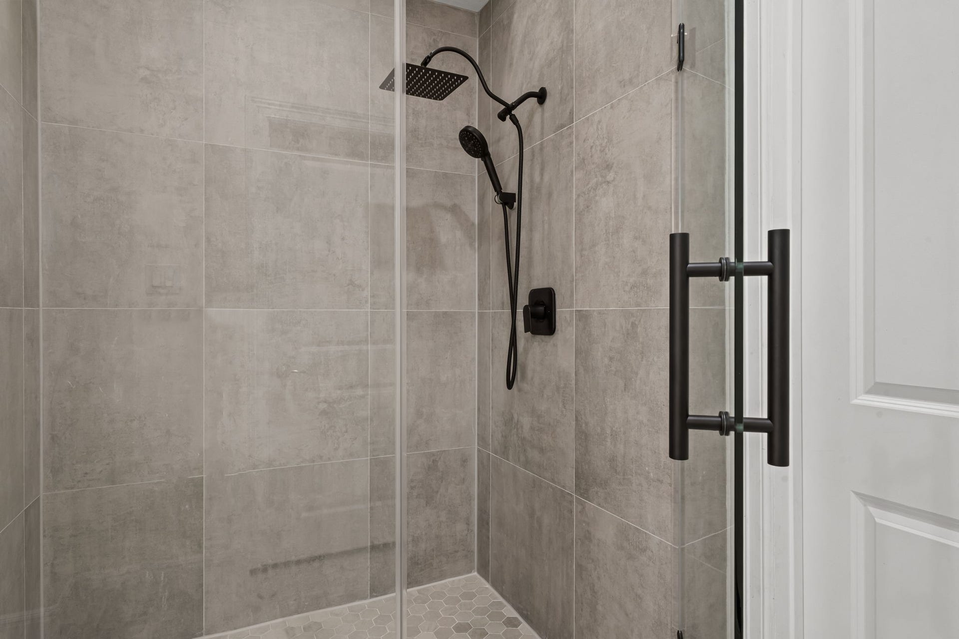 1423 Knox Street, Houston, TX 77007 A large walk-in shower features seamless glass, refined tilework, and modern fixtures. The streamlined design reinforces the renovated bath's sophisticated appeal.