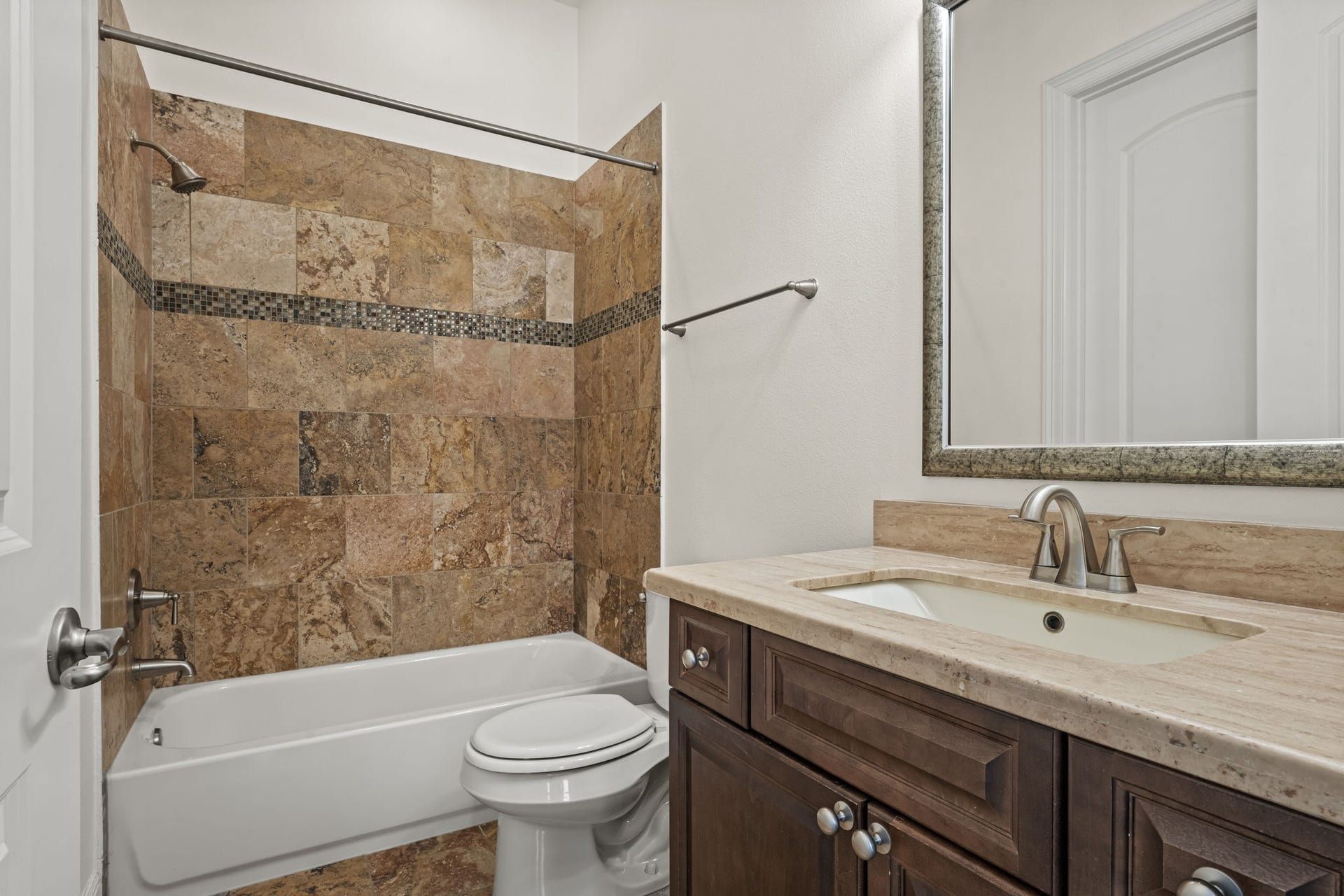 1423 Knox Street, Houston, TX 77007 The secondary bathroom is finished with a stone-topped vanity and coordinating tile. A tub-and-shower combination provides practical convenience for guests or household members.