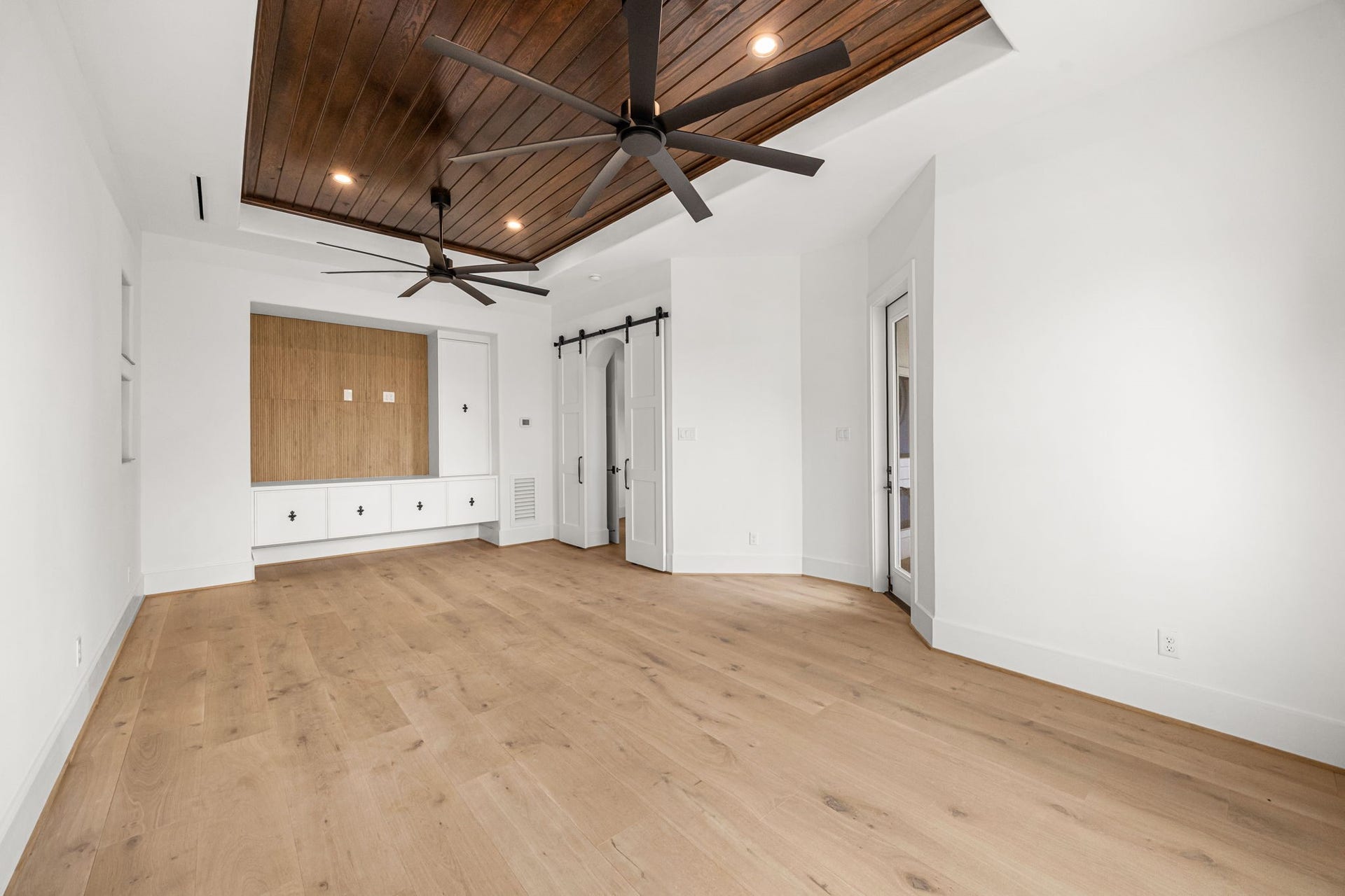 721 Harborside Way, League City, TX 77565 Another view highlights the custom floating cabinetry with dedicated TV space, complemented by stylish barn doors leading into the room.