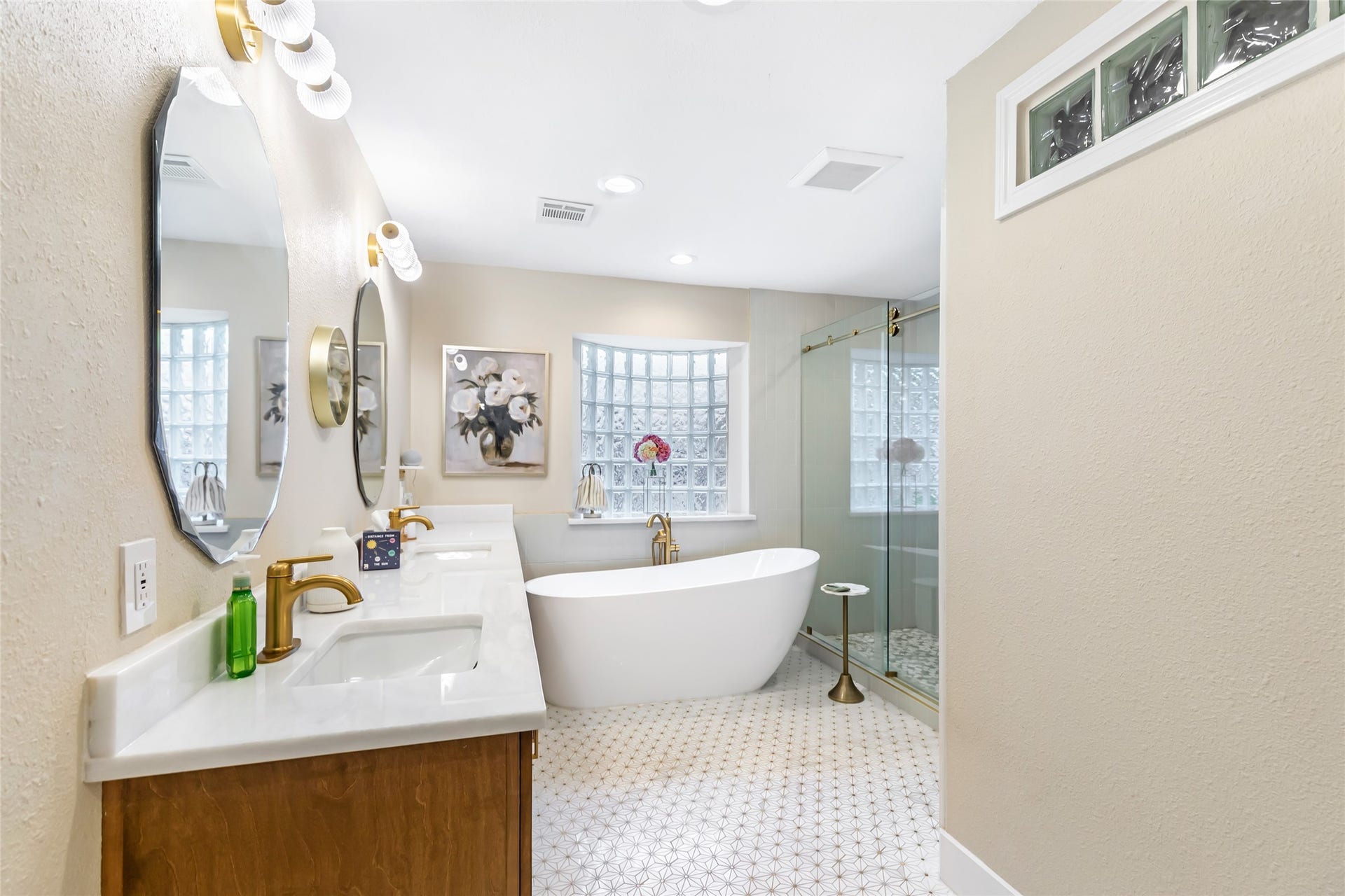 3714 Swift Creek Drive, Kingwood, TX 77339 Luxurious bathroom featuring a sleek freestanding tub, dual vanity with gold fixtures, elegant mirrors, and a spacious glass-enclosed shower, all enhanced by soft lighting and stylish decor.
