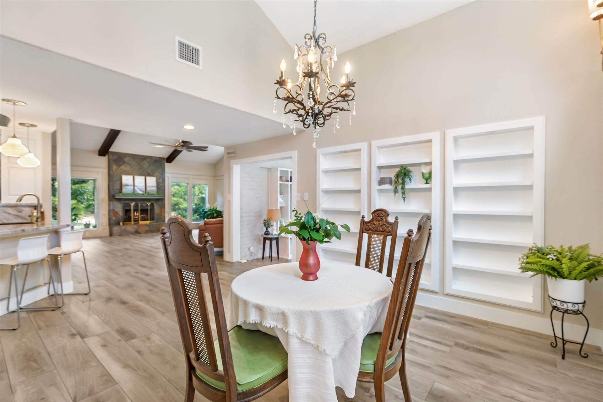 3714 Swift Creek Drive, Kingwood, TX 77339 Elegant open-concept living space featuring a cozy dining area with a classic chandelier, built-in shelving, and a seamless flow into the bright kitchen and living room with a charming fireplace.
