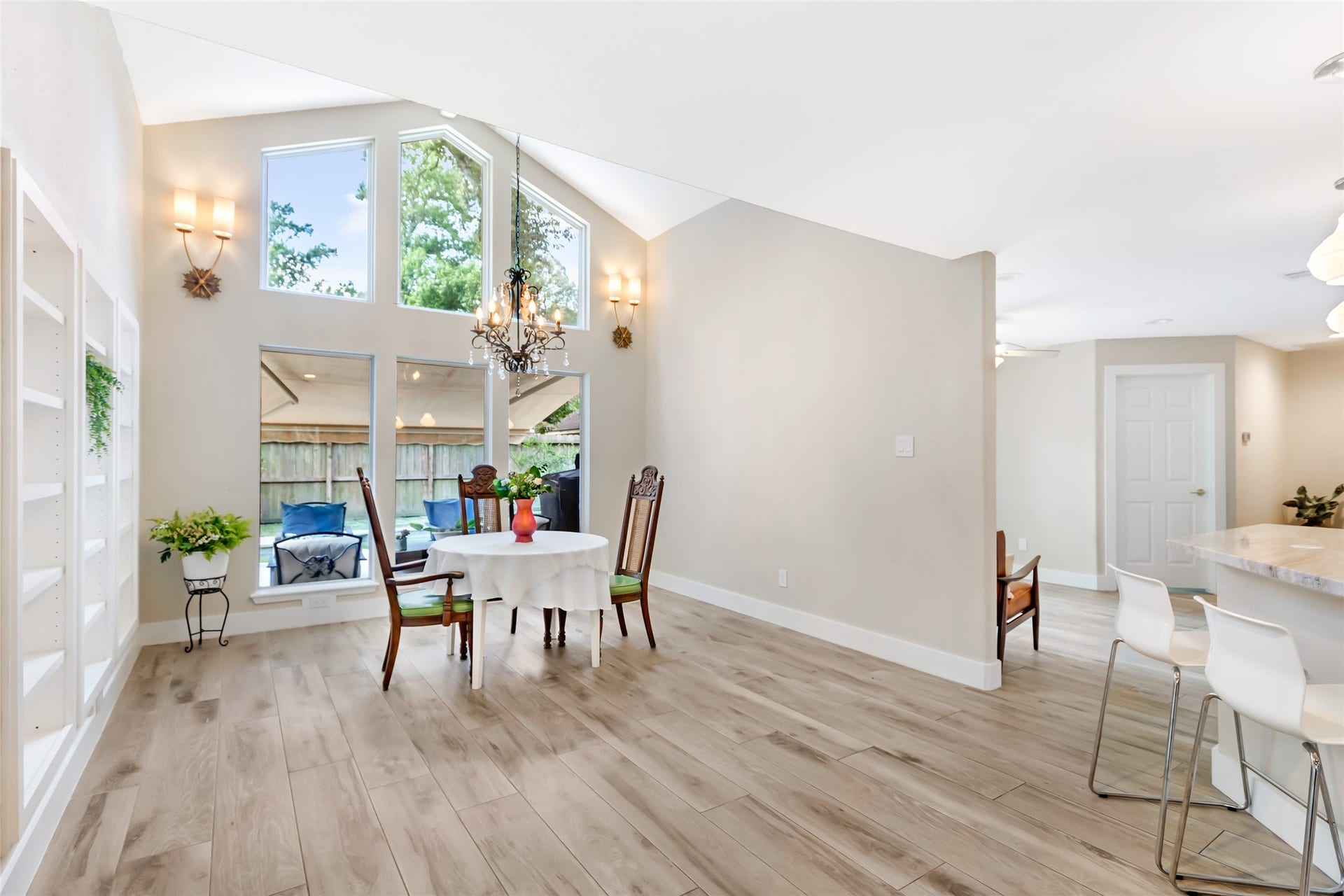 3714 Swift Creek Drive, Kingwood, TX 77339 Bright and inviting dining area with high ceilings, large windows, and elegant chandelier, seamlessly connected to a modern kitchen with a breakfast bar.