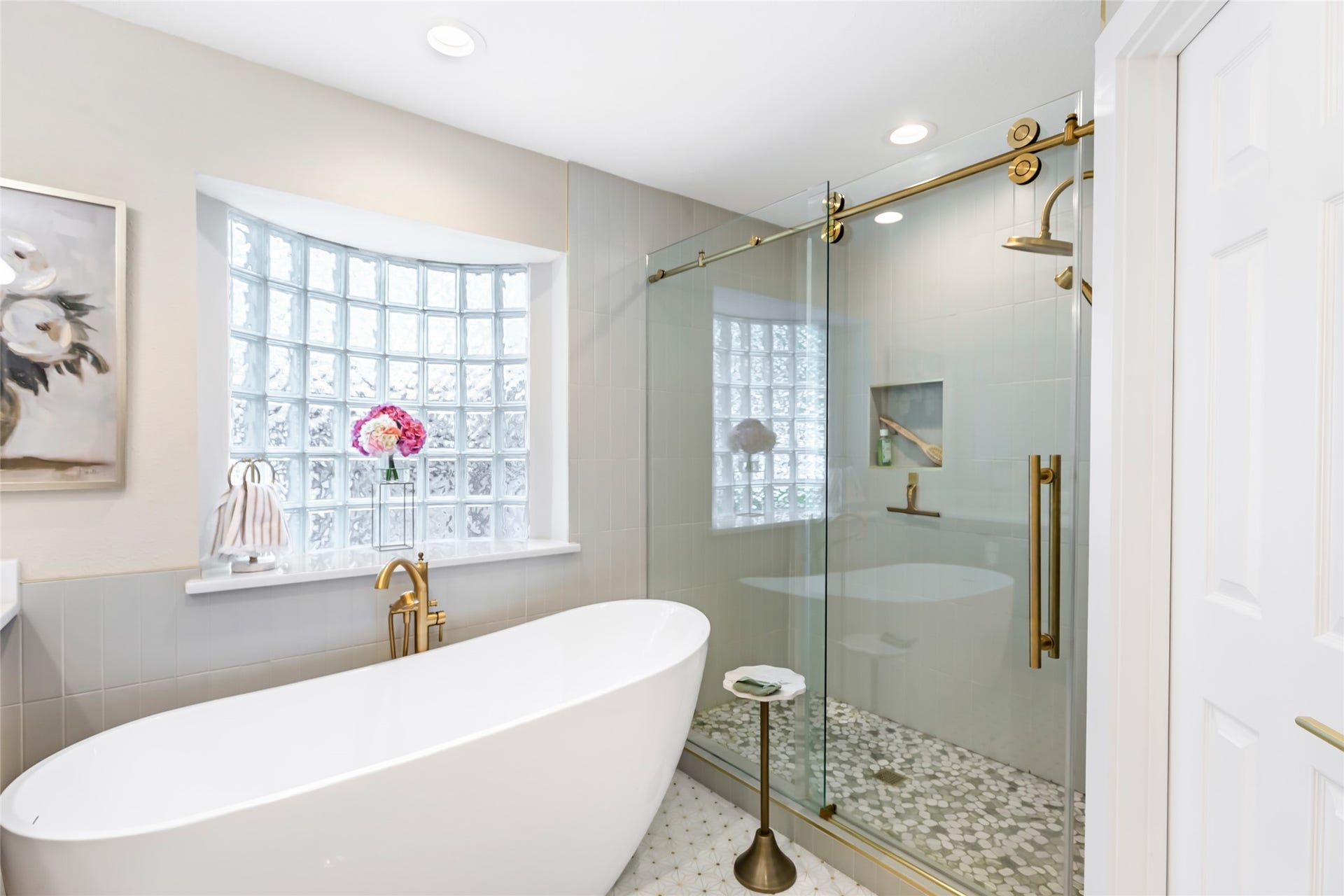 3714 Swift Creek Drive, Kingwood, TX 77339 Luxurious bathroom featuring a sleek freestanding tub and elegant glass-enclosed shower, complemented by a stylish brass finish and a light-filled glass block window.