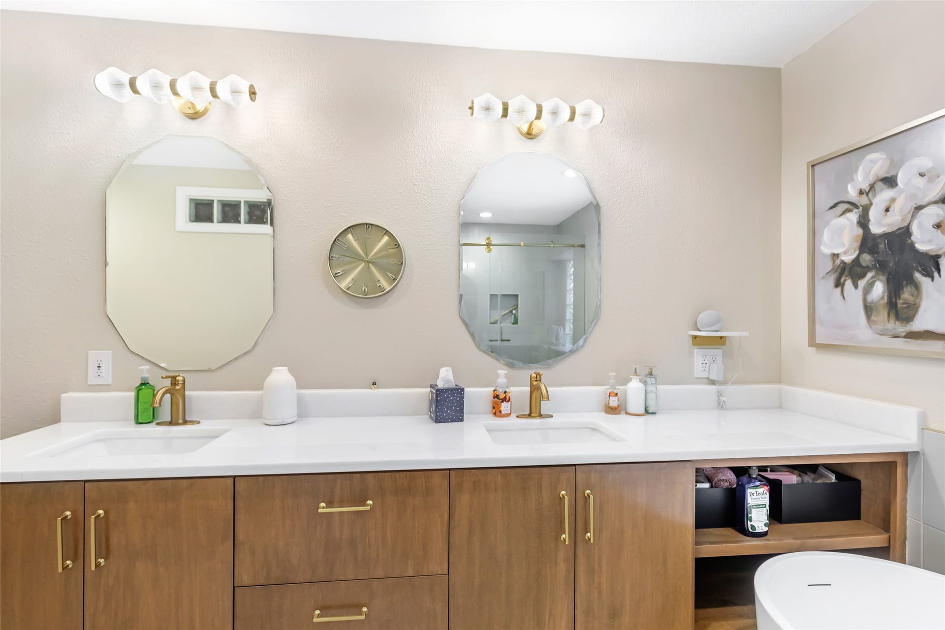 3714 Swift Creek Drive, Kingwood, TX 77339 Elegant bathroom featuring dual sinks with sleek wooden cabinetry, modern gold fixtures, and chic hexagonal mirrors.