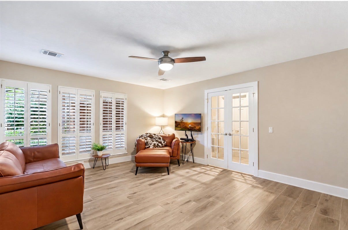 3714 Swift Creek Drive, Kingwood, TX 77339 Bright and inviting living space featuring elegant ceramic wood flooring, comfortable seating, and ample natural light through plantation shutters. A versatile area perfect for relaxation or a home office setup.