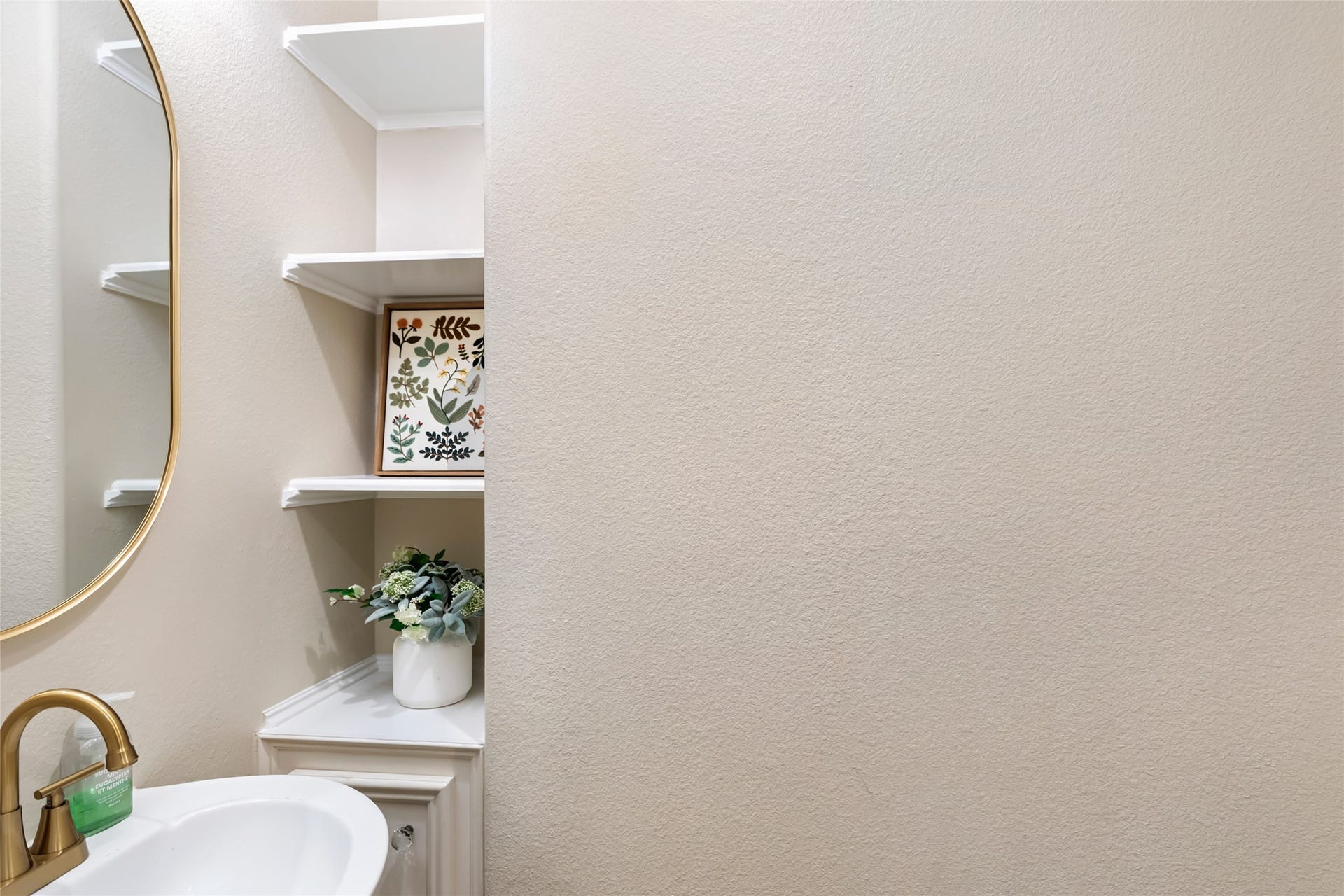 3714 Swift Creek Drive, Kingwood, TX 77339 Elegant half bath with a modern gold faucet, sleek white sink, and stylish corner shelving for added decor and storage.