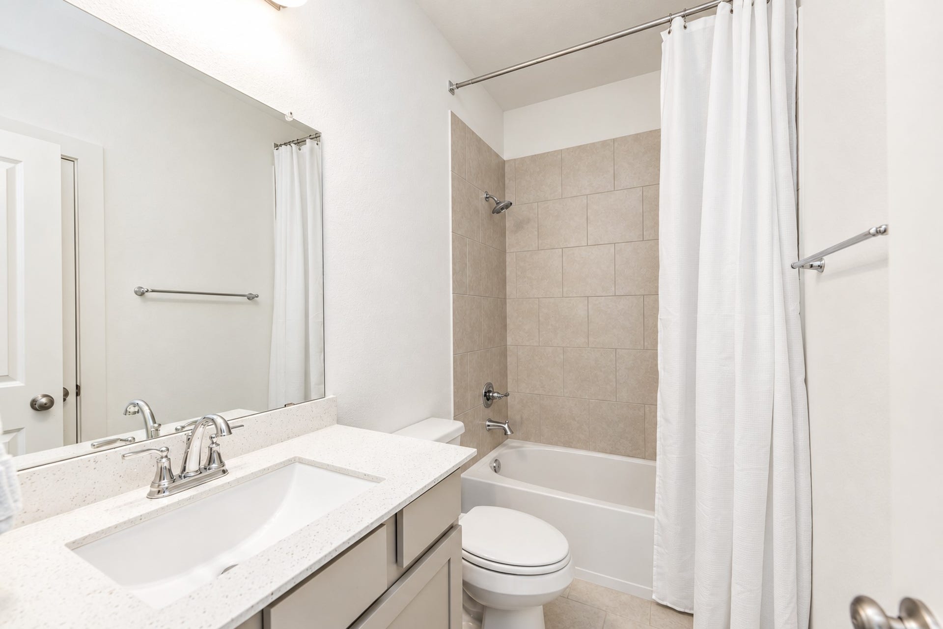 16922 Warm Glow Court, Hockley, TX 77447 Bright and modern bathroom featuring a sleek vanity with ample counter space, a large mirror, and a classic shower-tub combination with neutral tile accents.